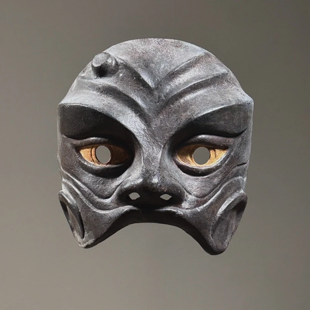 Front view of Jean-Pierre Maury modernist leather harlequin mask on neutral gray background.