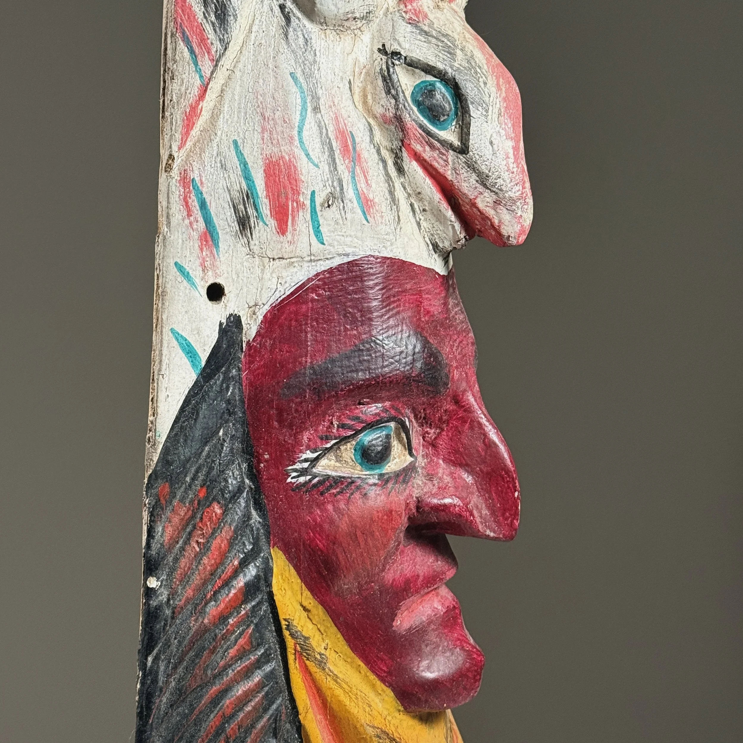 Close-up of hand-carved facial features and painted red surface.