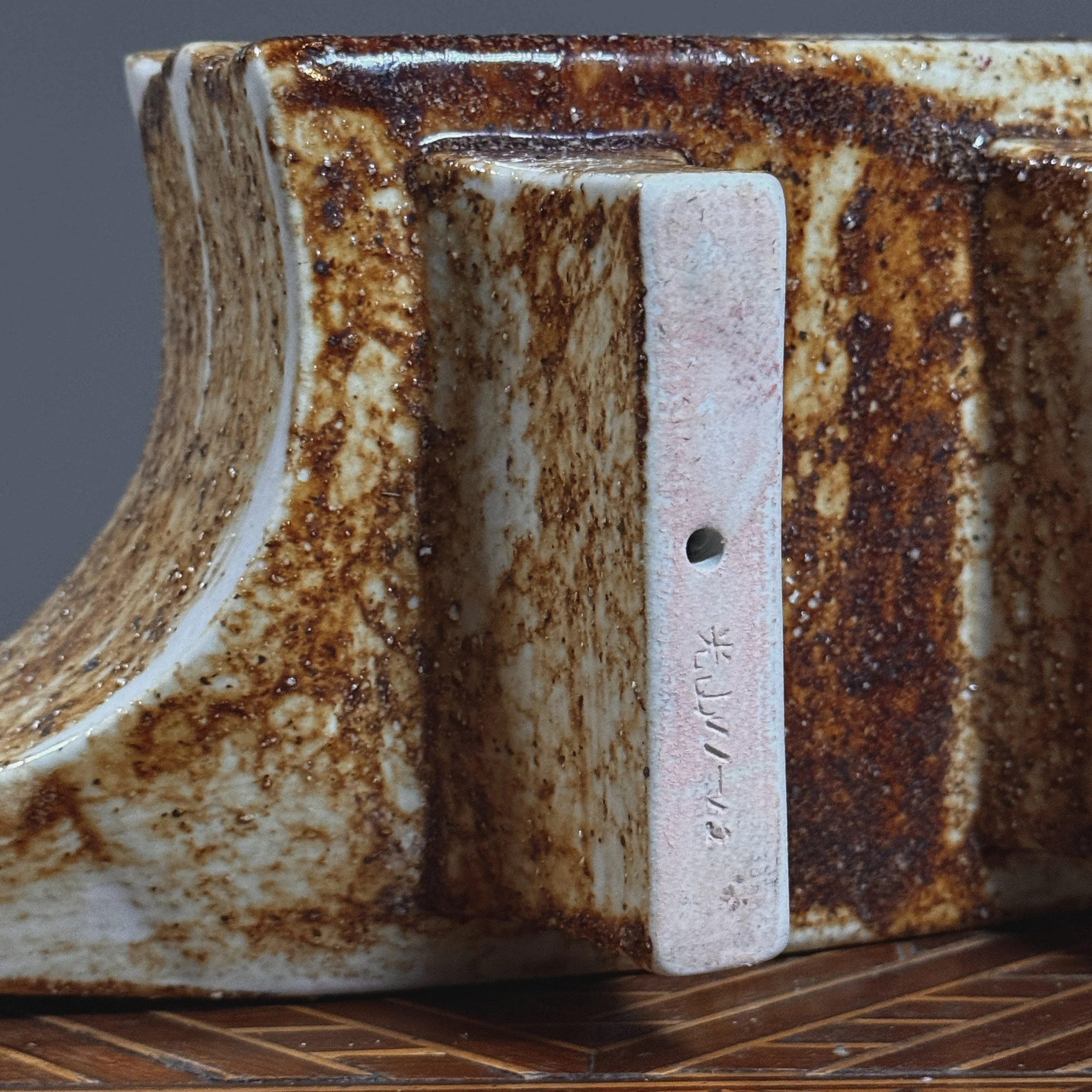 View of the base, showing the block footing and artist's signature.