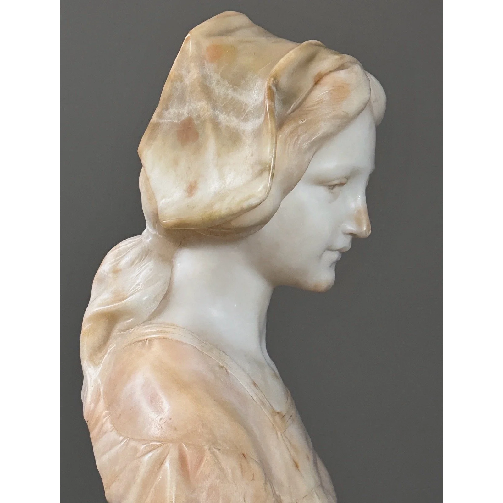 Close-up side angle detail of the woman's softly carved facial features and expression.