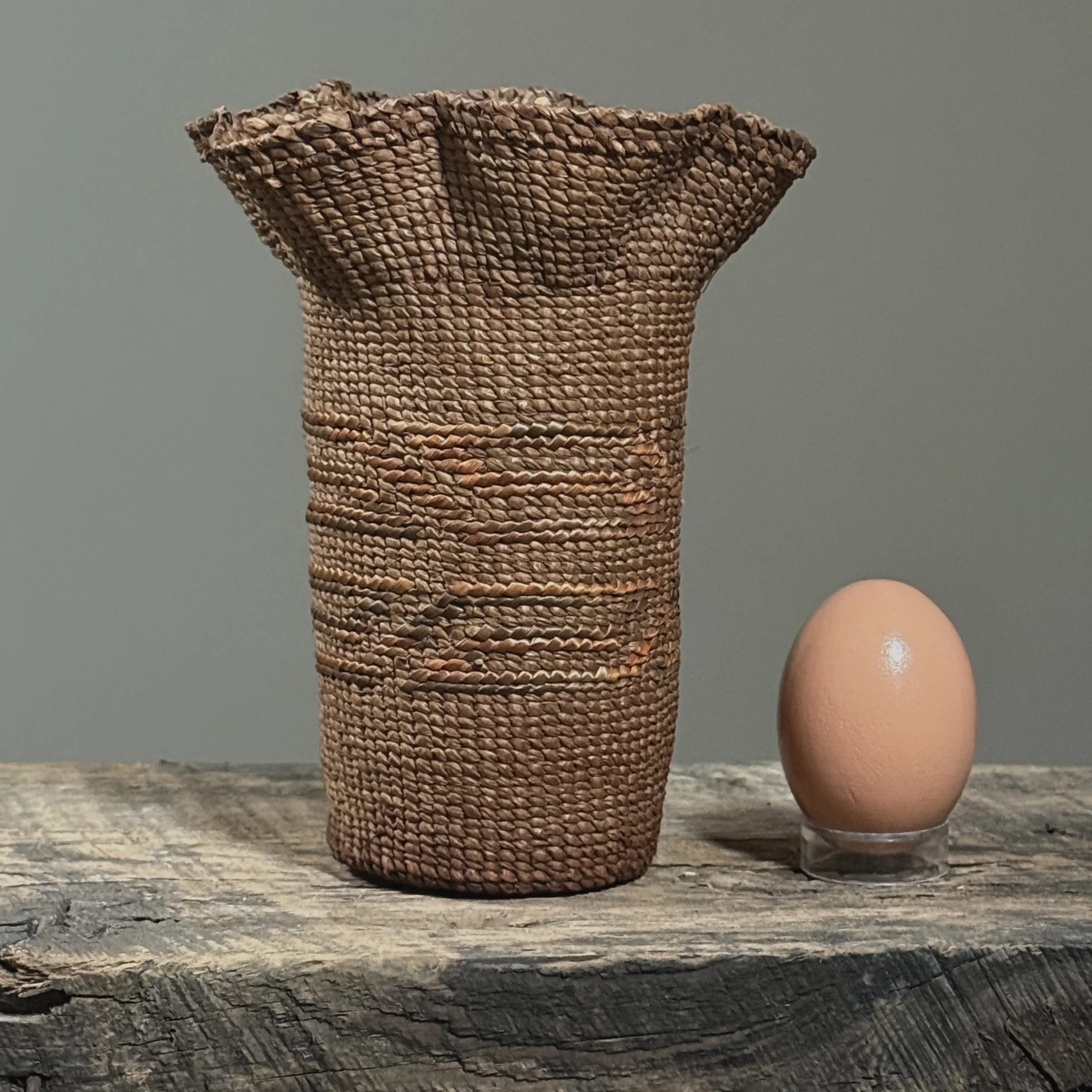Rare small Tlingit woven cedar vessel from Ketchikan with egg for size reference.