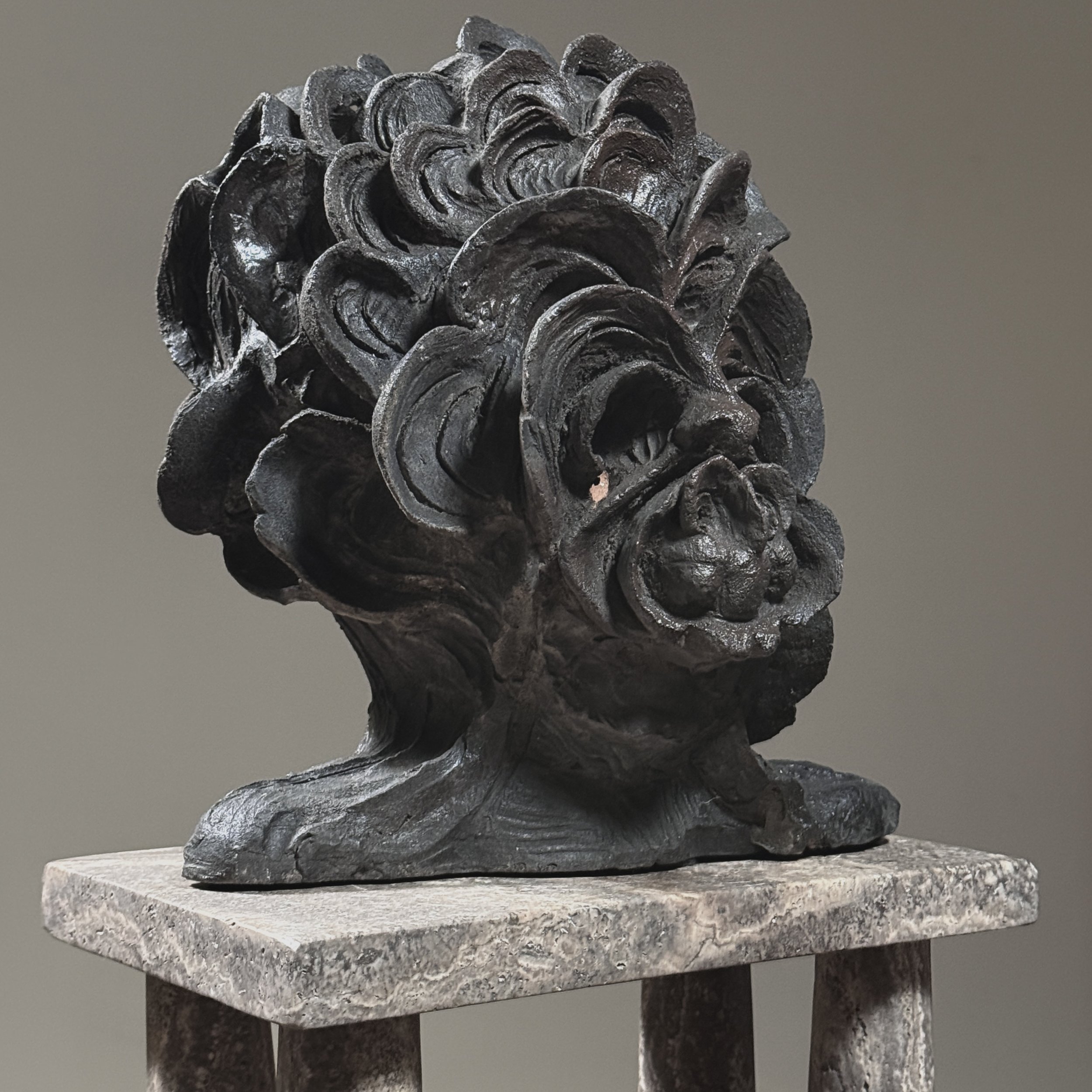 Three-quarter view. Sculpture weight and density visible. Hand-modeled texture.