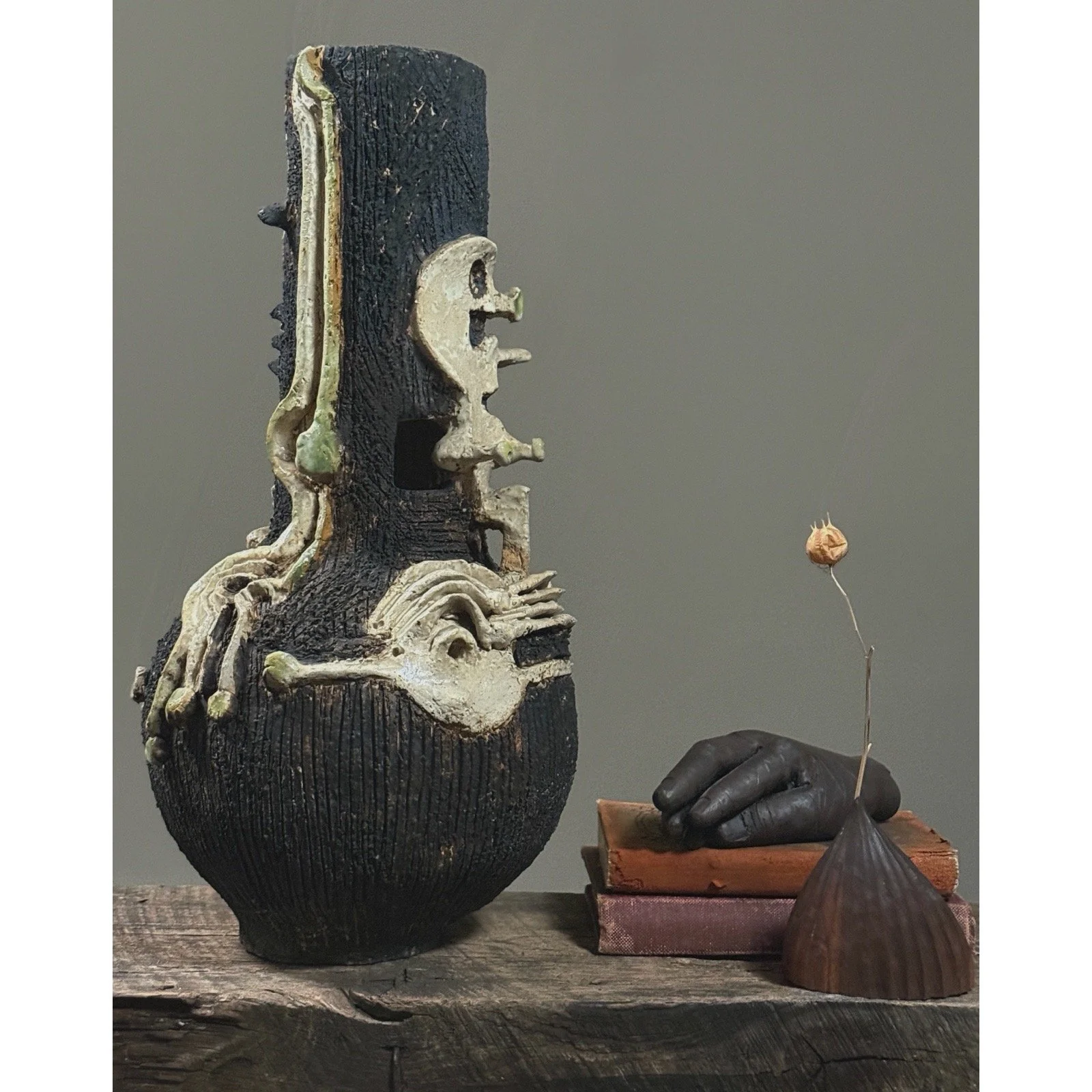 Large sculptural vase featuring bone-like fragments and a skull figure vignette with metal hand.
