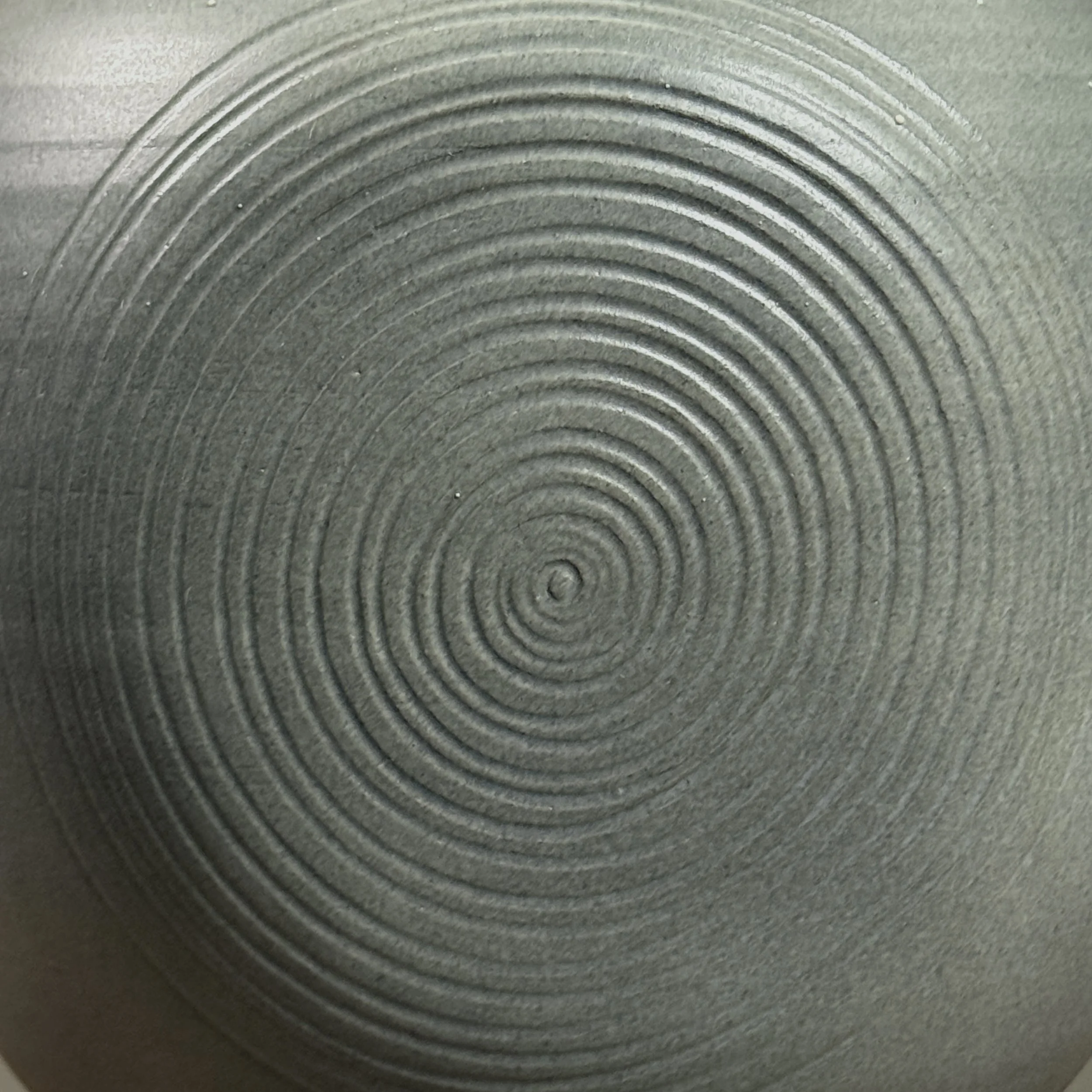 Detail of etched swirl design on muted grey-blue surface