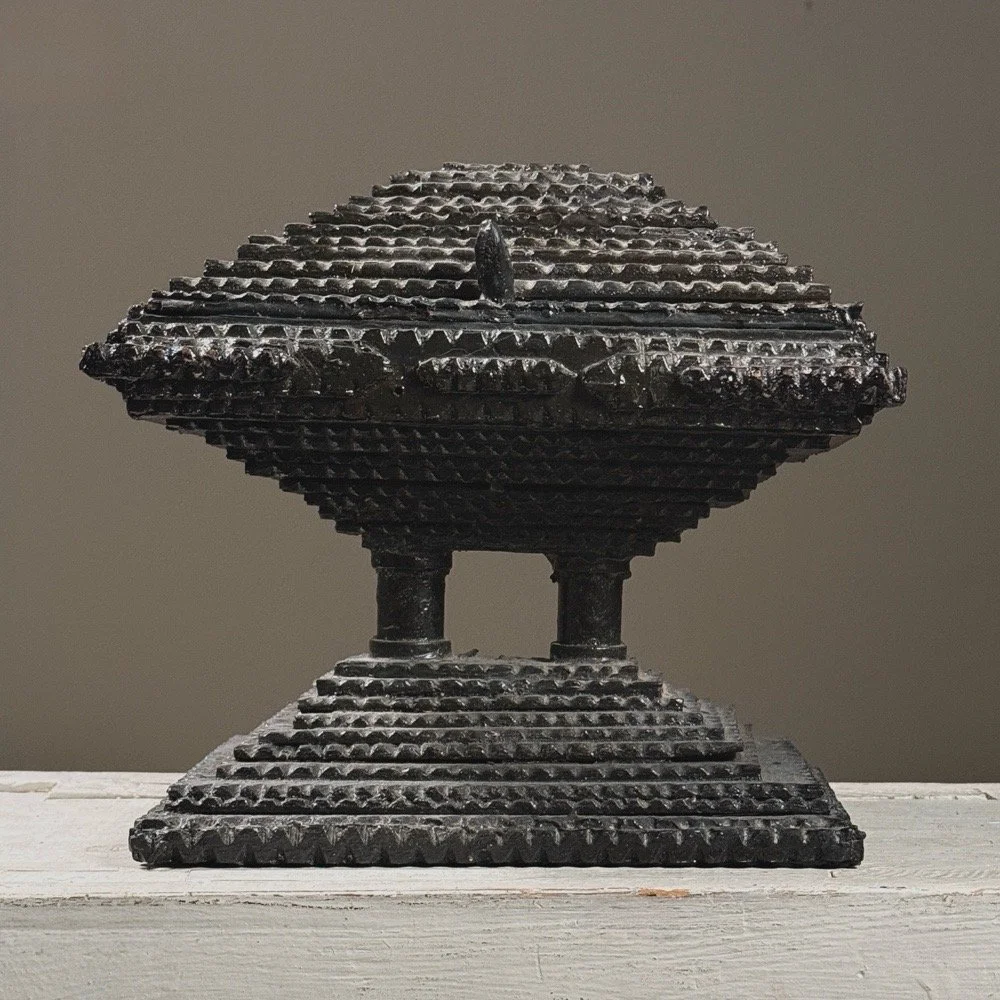 Full frontal view of an antique black painted chip-carved tiered tramp art box with hinged top