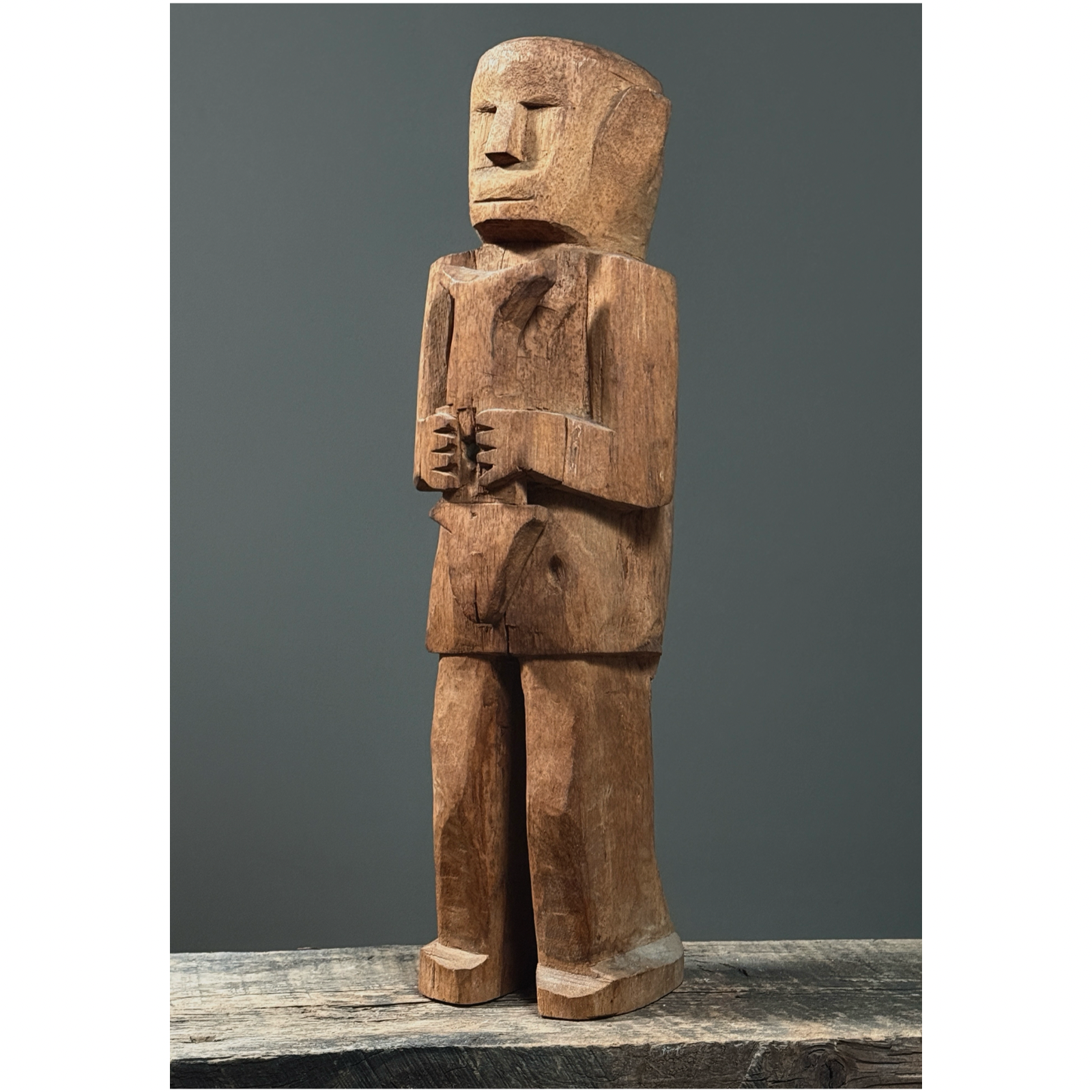 Front view of hand-carved wood folk art figure of man holding a fish