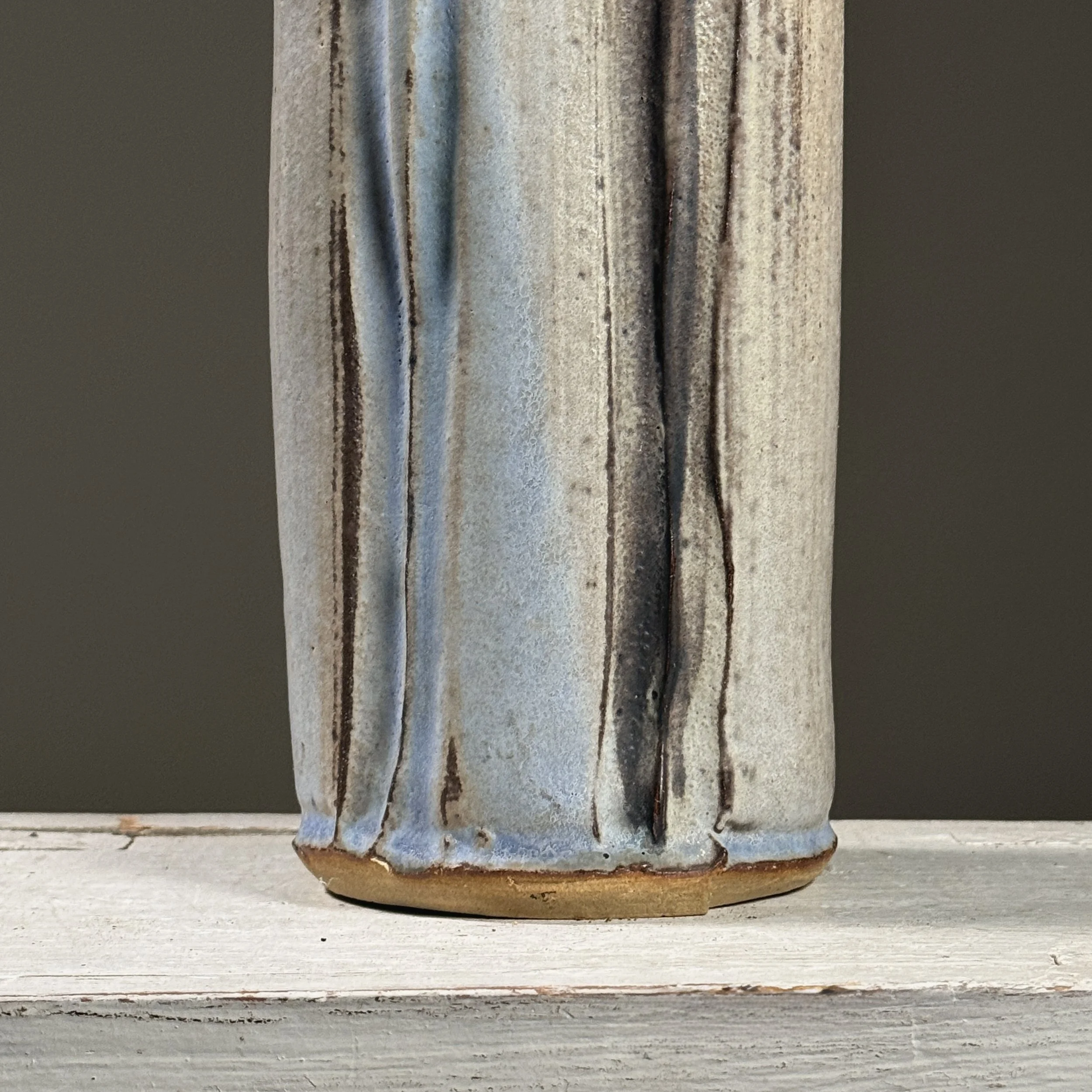 Close-up detail of wood-fired surface effects including pale blue streaks and speckled grey markings