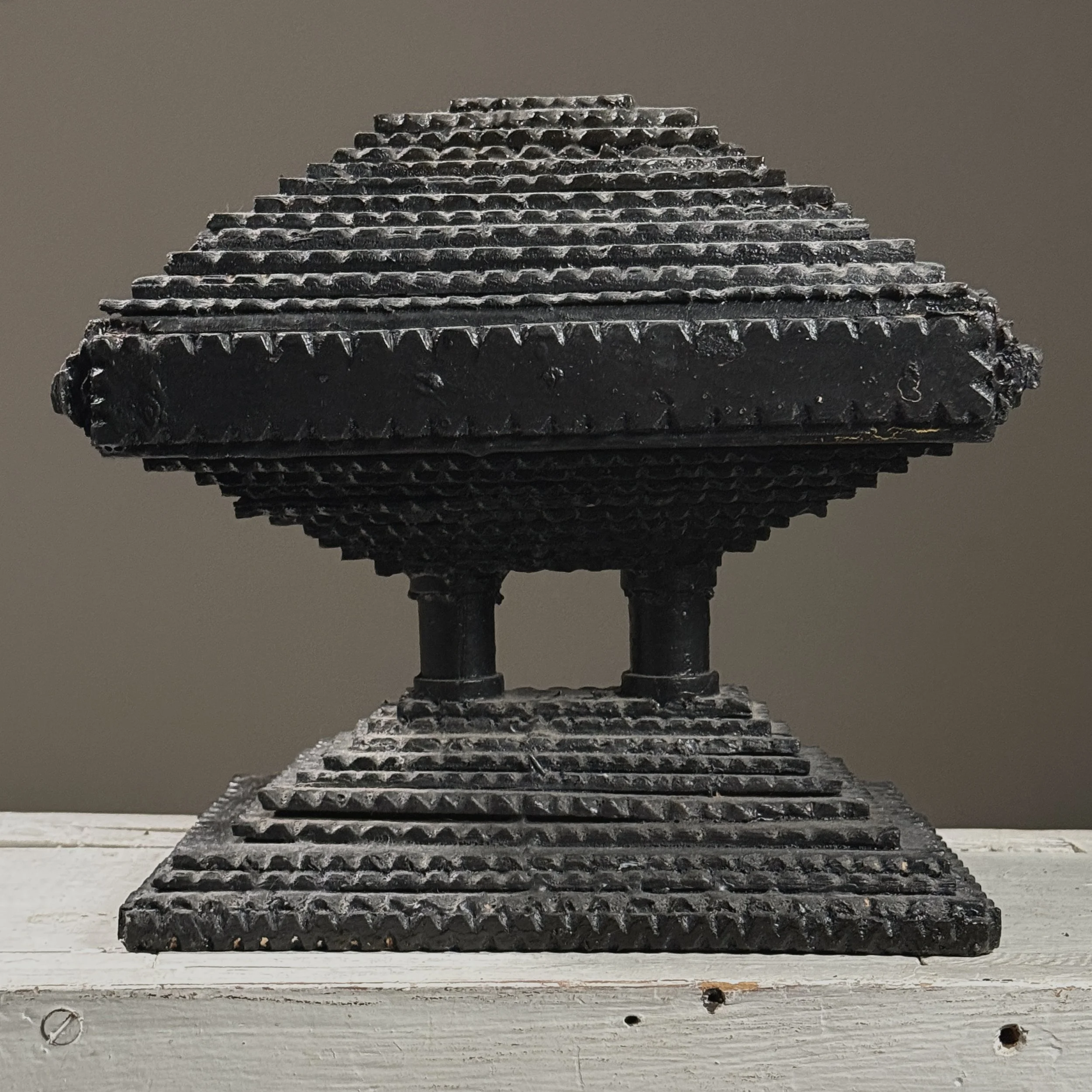 Full frontal view of an antique black painted chip-carved tiered tramp art box with hinged top