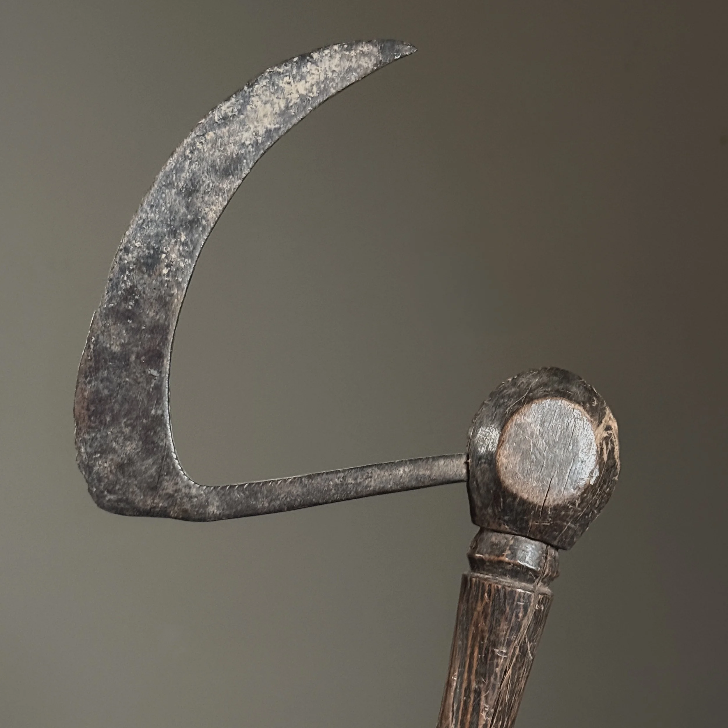 Close-up detail of the carved face where iron blade meets wooden handle