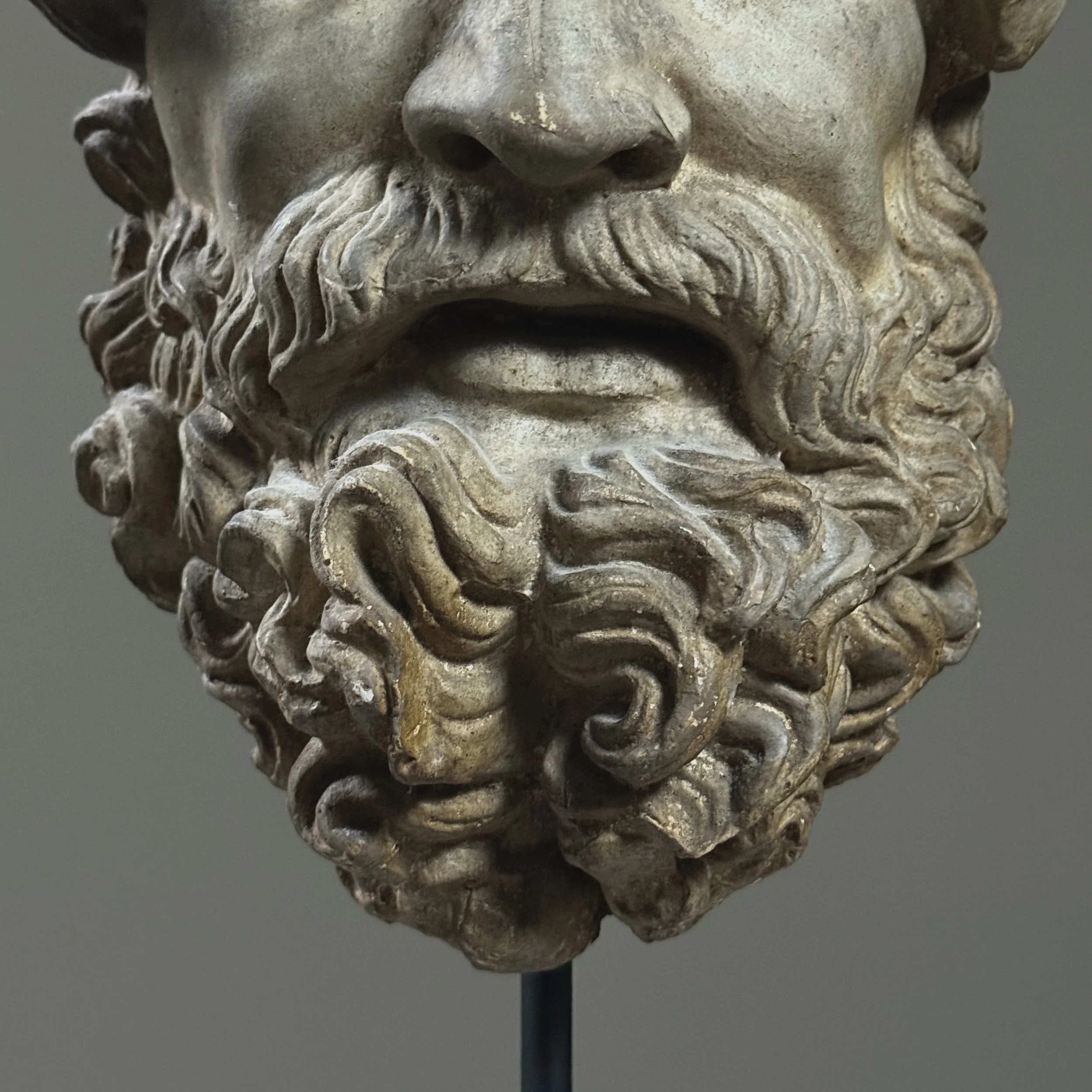 Close-up of the grape cluster and leaf wreath crown on the mythological head.