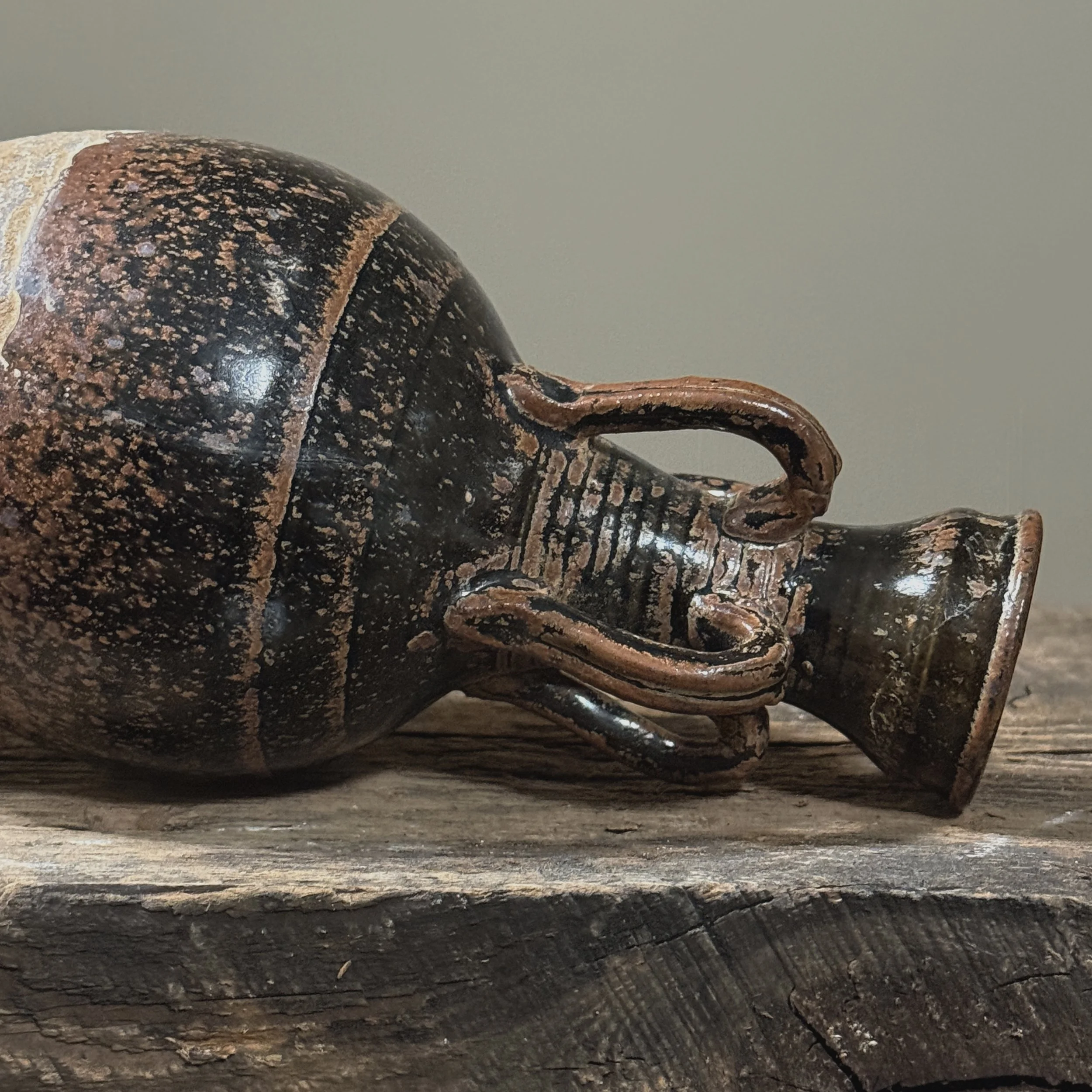 Close-up detail of mottled brown speckled glaze on antique four handled stoneware vessel, showing glaze texture