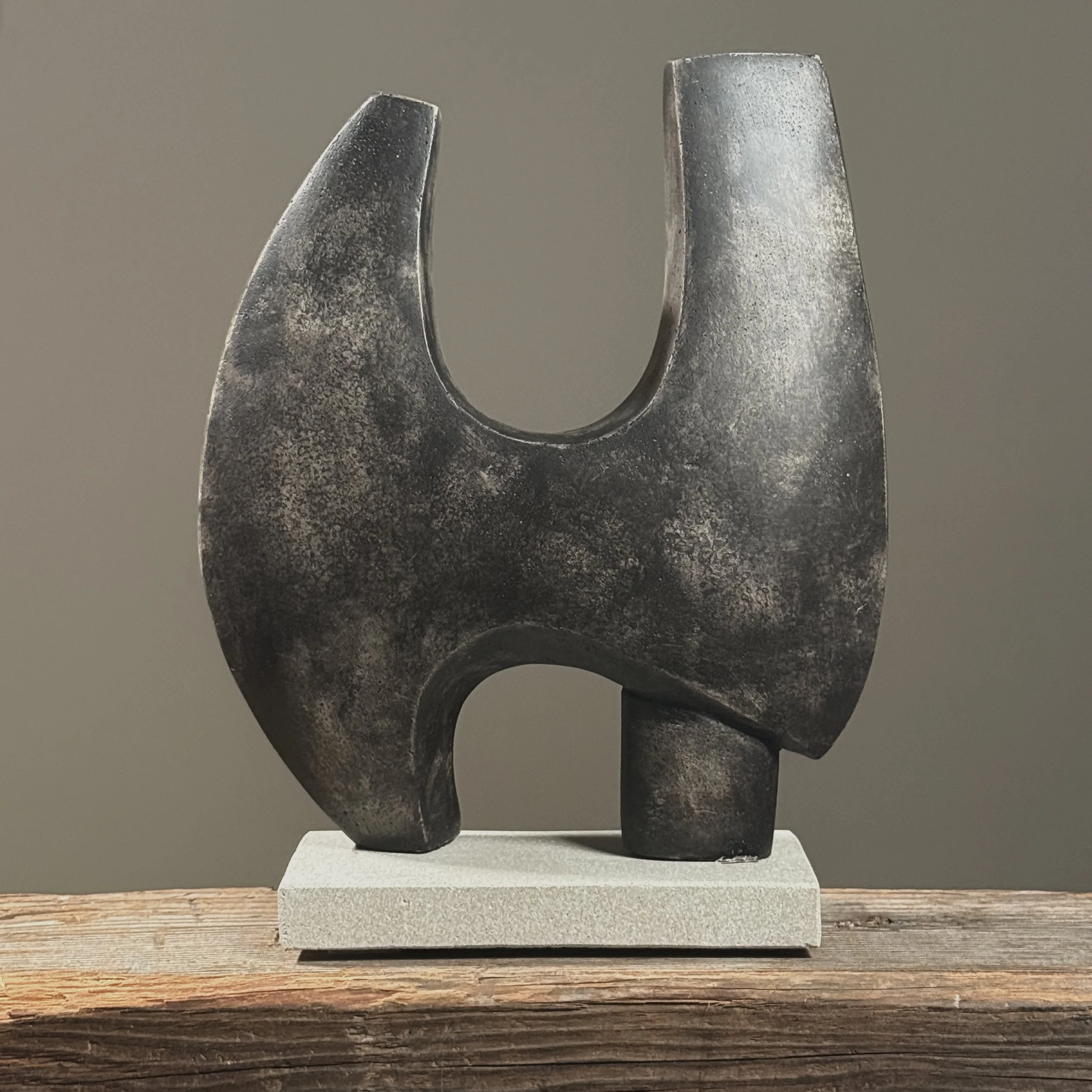 Full frontal view of a modernist biomorphic cement sculpture with dark grey mottled patina and winged form