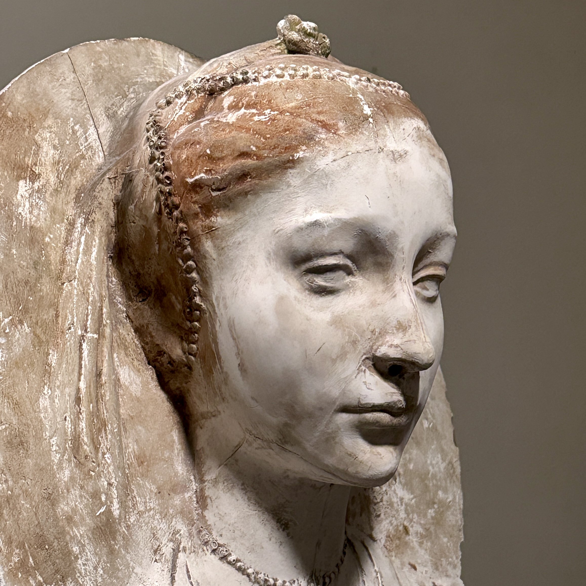 Detail of the female face, hair, and draped headdress.