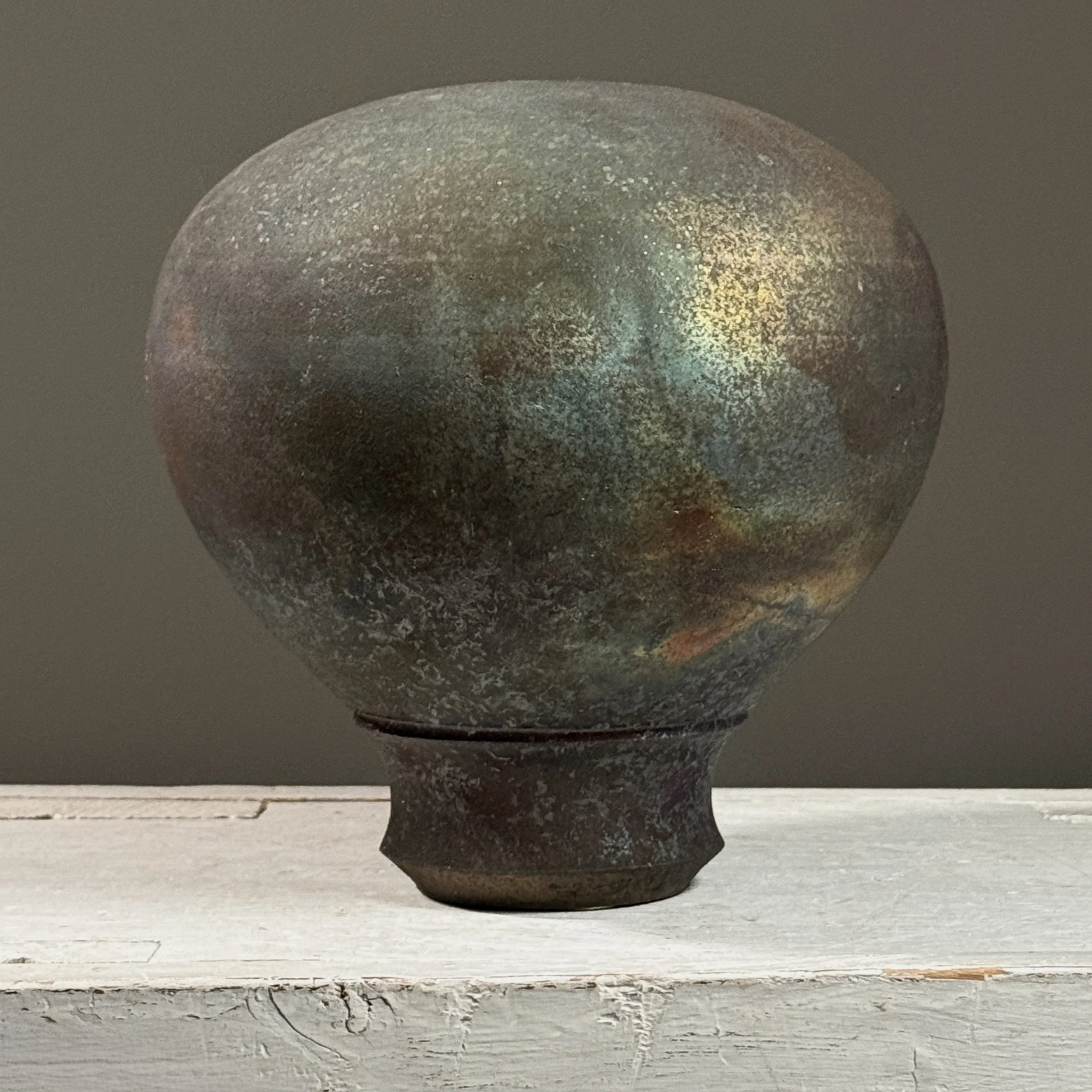 Vintage postmodern raku fired footed black stoneware vessel. 7.18 inches high by 6.75 inches diameter.