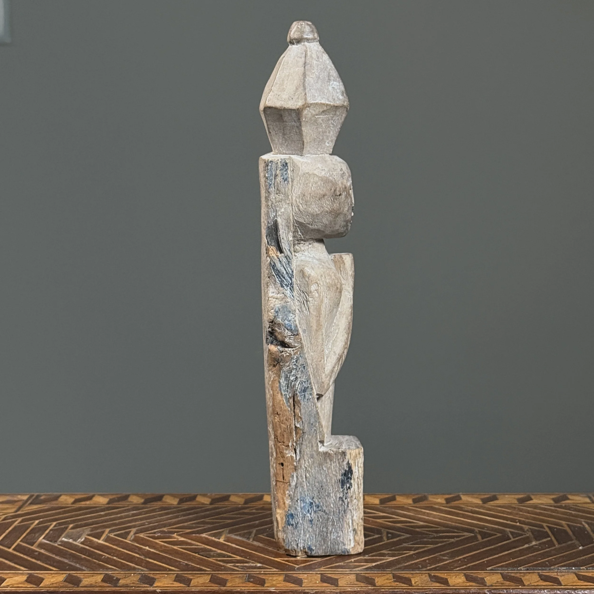Whitewashed Indonesian wooden figure finial, side view.