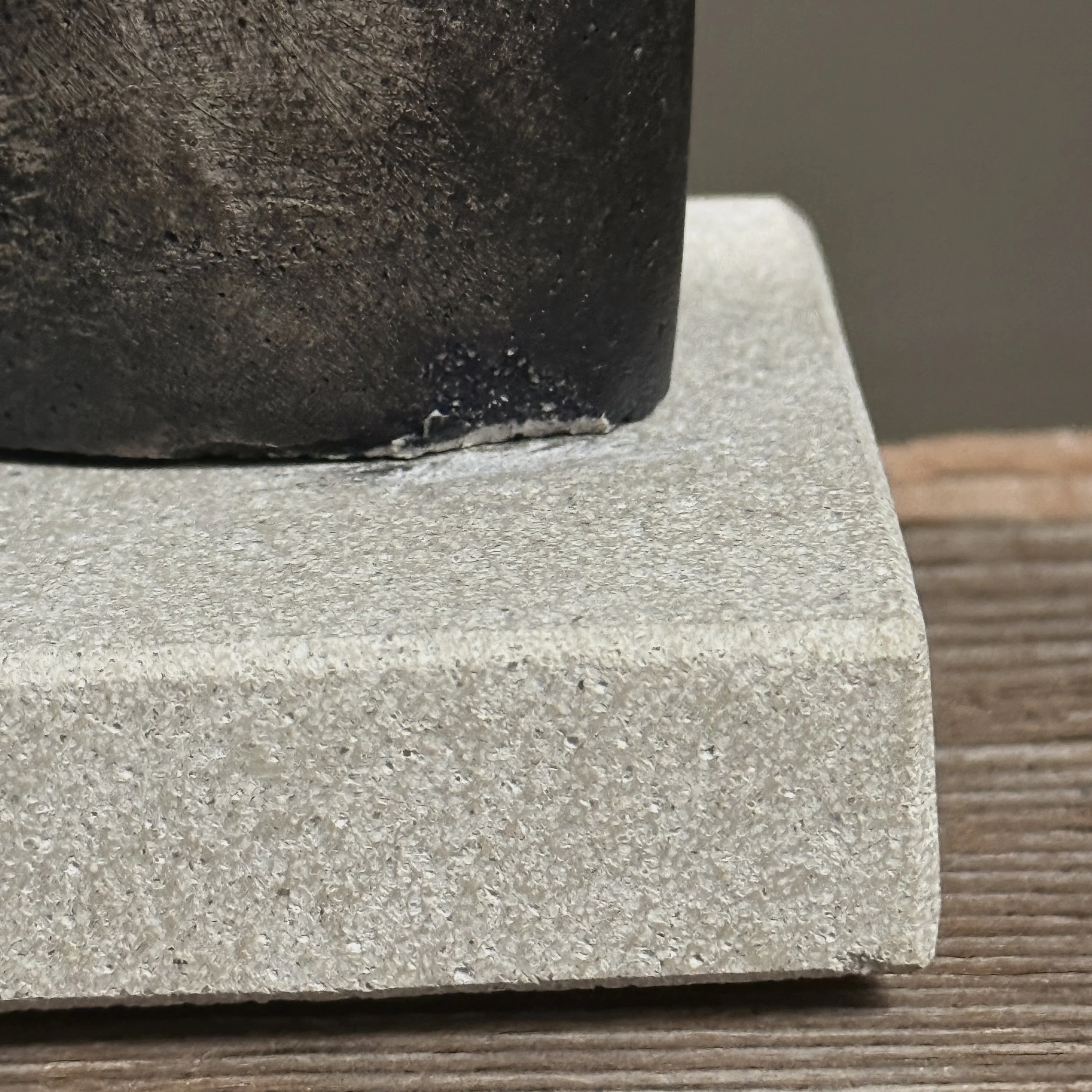 View emphasizing the contrast between dark grey sculpture and lighter cement-colored base