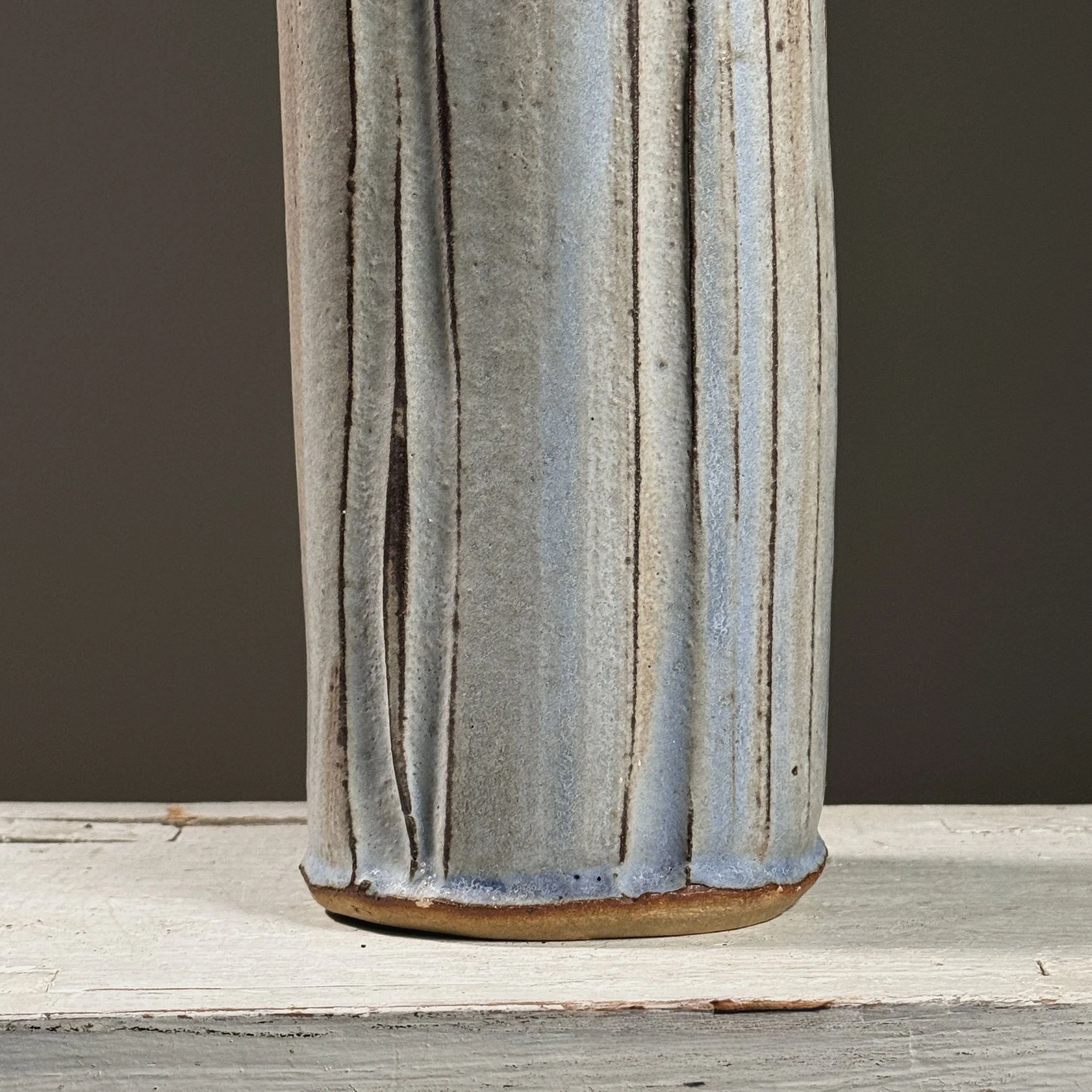 Close-up detail of wood-fired surface effects including pale blue streaks and speckled grey markings