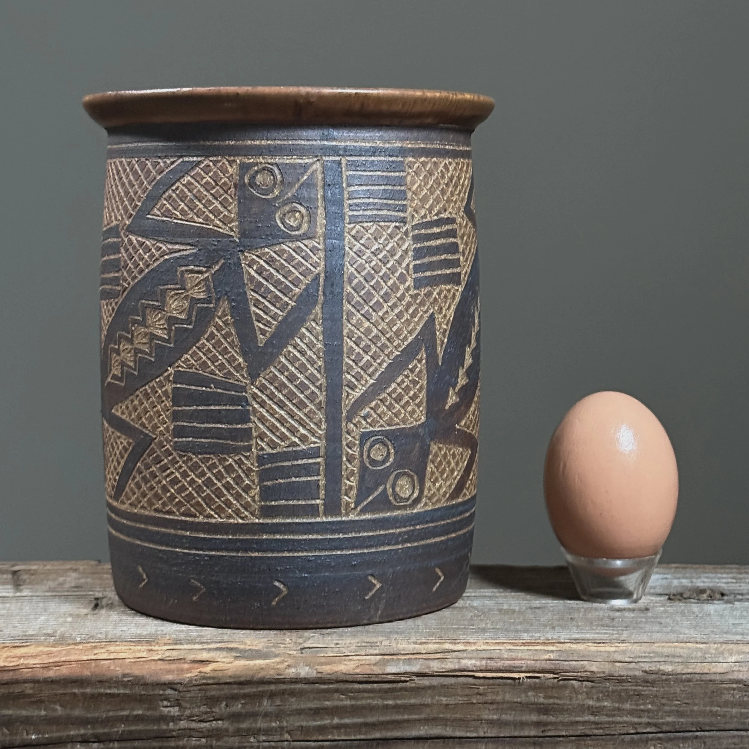 Full frontal view of a vintage sgraffito ceramic vase with incised lizard decoration, signed Tinsman 1992 With egg for size reference.
