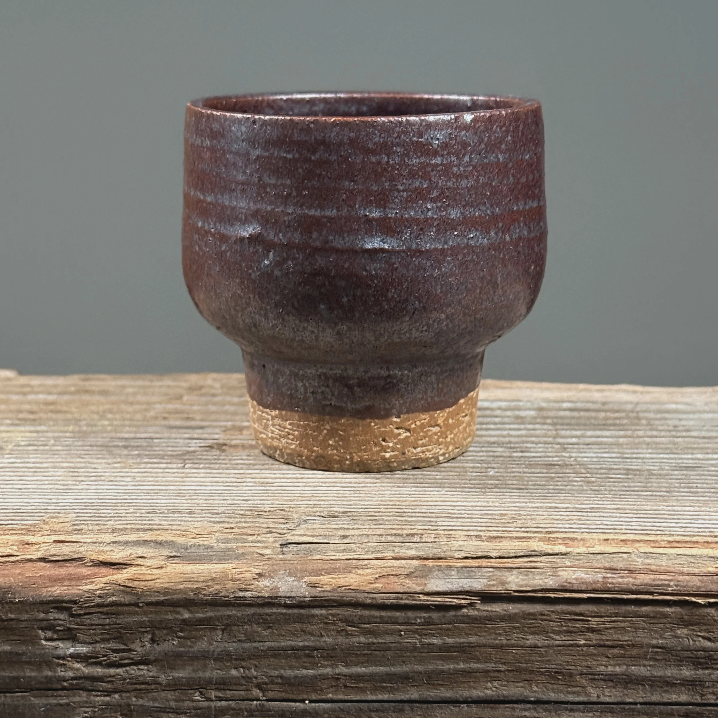 Maroon metallic yunomi cup. Deep maroon surface. Faint blue undertone visible at rim under light.