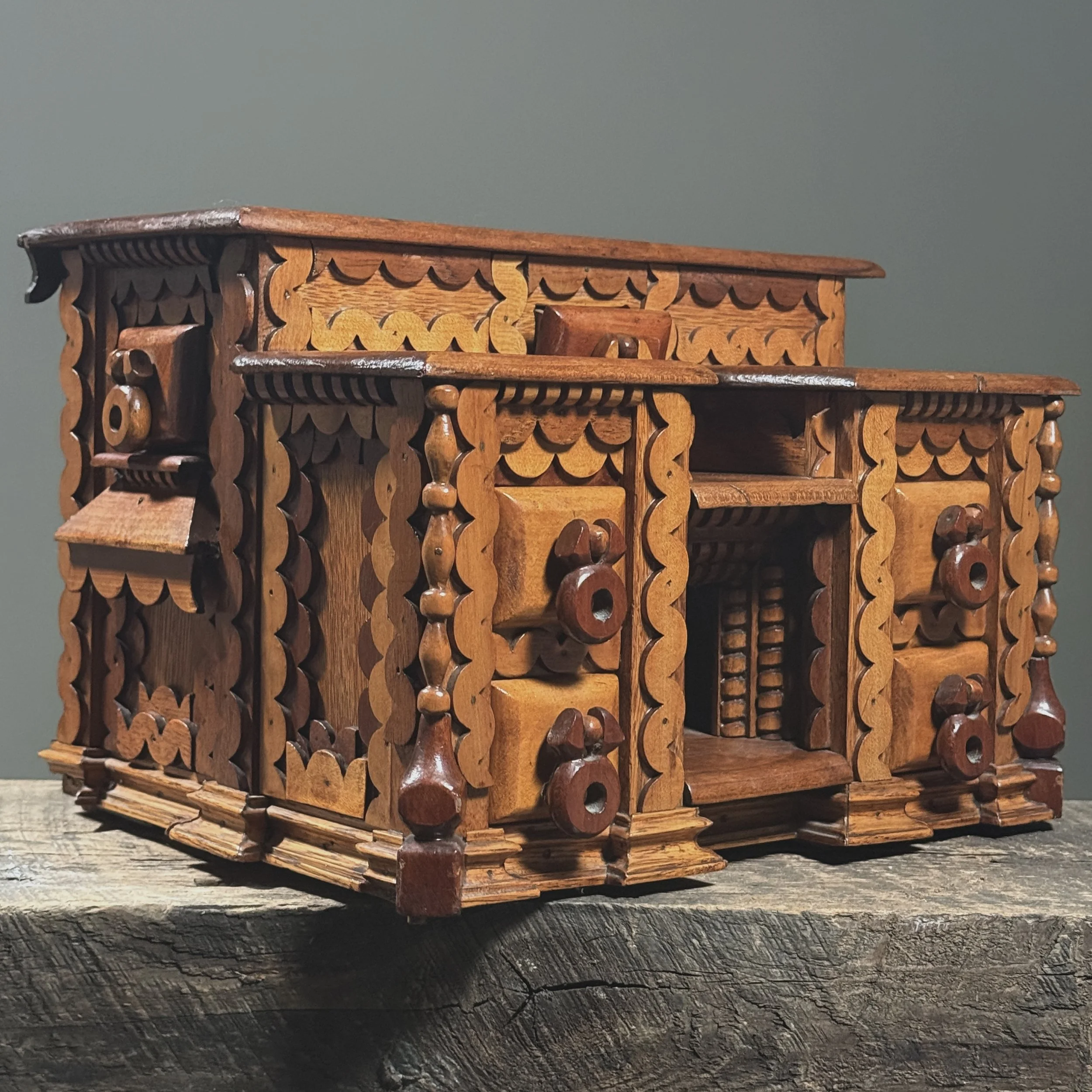 Three-quarter view of a heavily decorated scrollwork box featuring five front drawers and side drawers