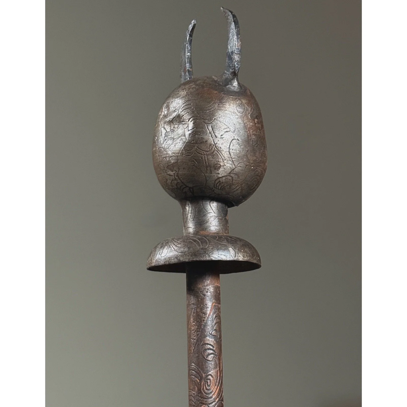 Reverse view of mace head revealing engraved figural representations of two human figures.