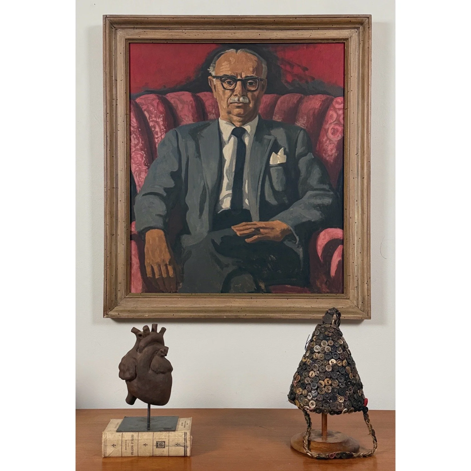 Vintage hand-built clay heart sculpture on black stand, vignette view.