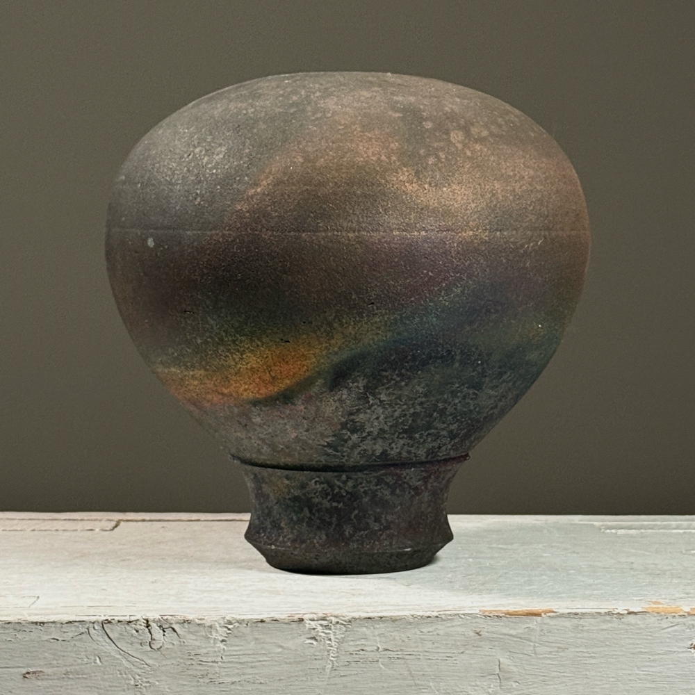Vintage postmodern raku fired footed black stoneware vessel. 7.18 inches high by 6.75 inches diameter.