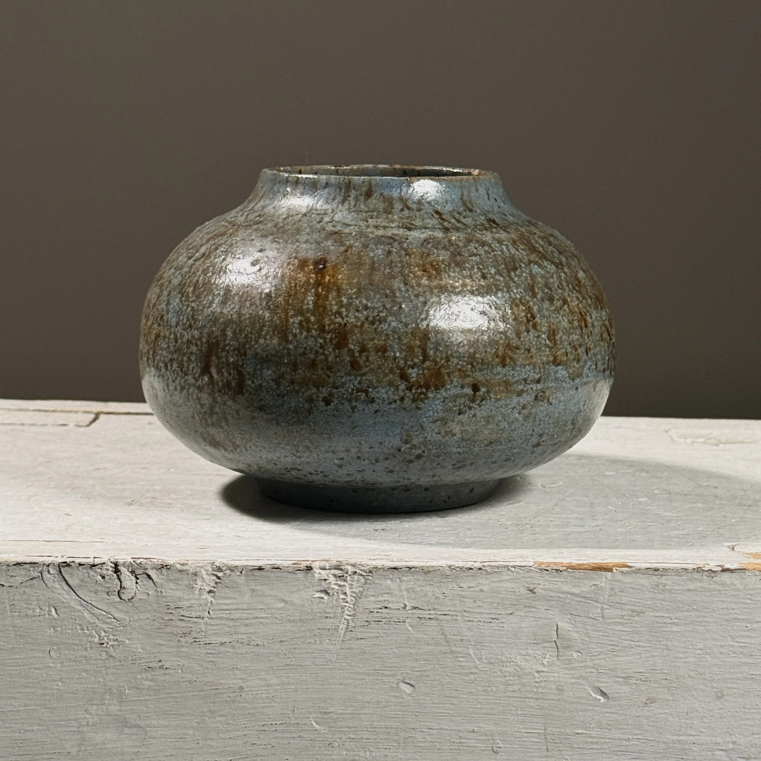 Front view of a vintage muted blue and brown splatter glaze ceramic vase.