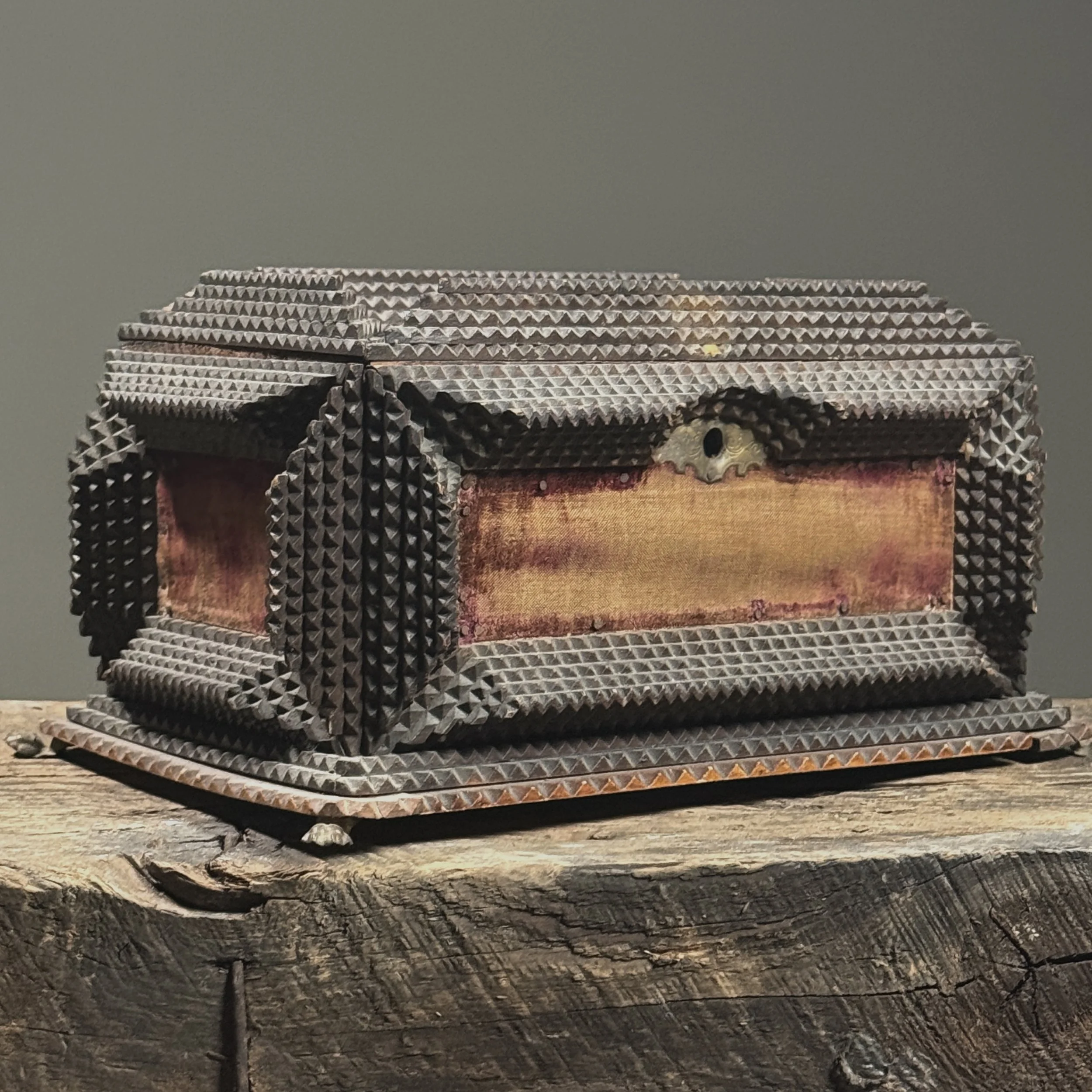 Three-quarter view showing chip-carved wood and velvet inserts.