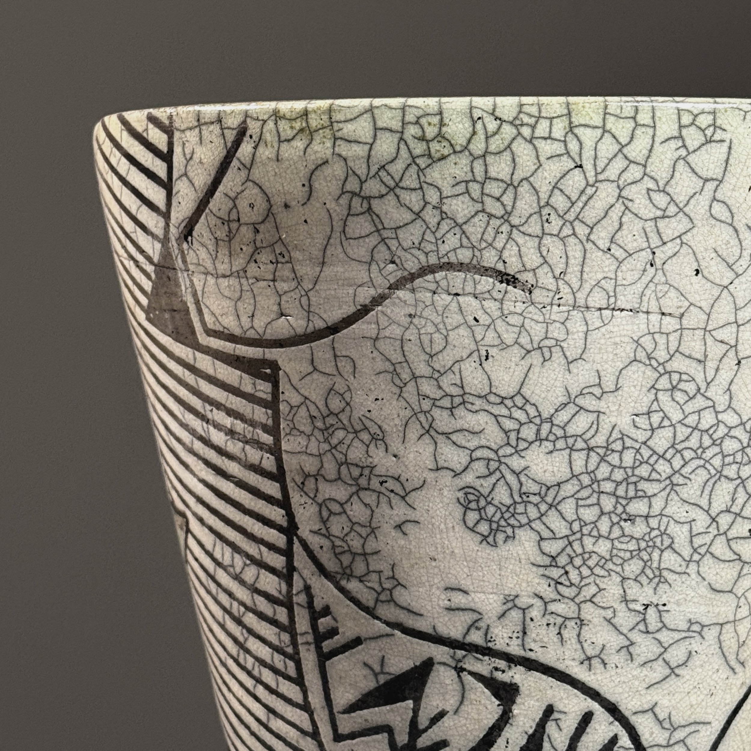 Close-up of blue-green glaze areas on vintage raku vessel with crackle surface and black line detail