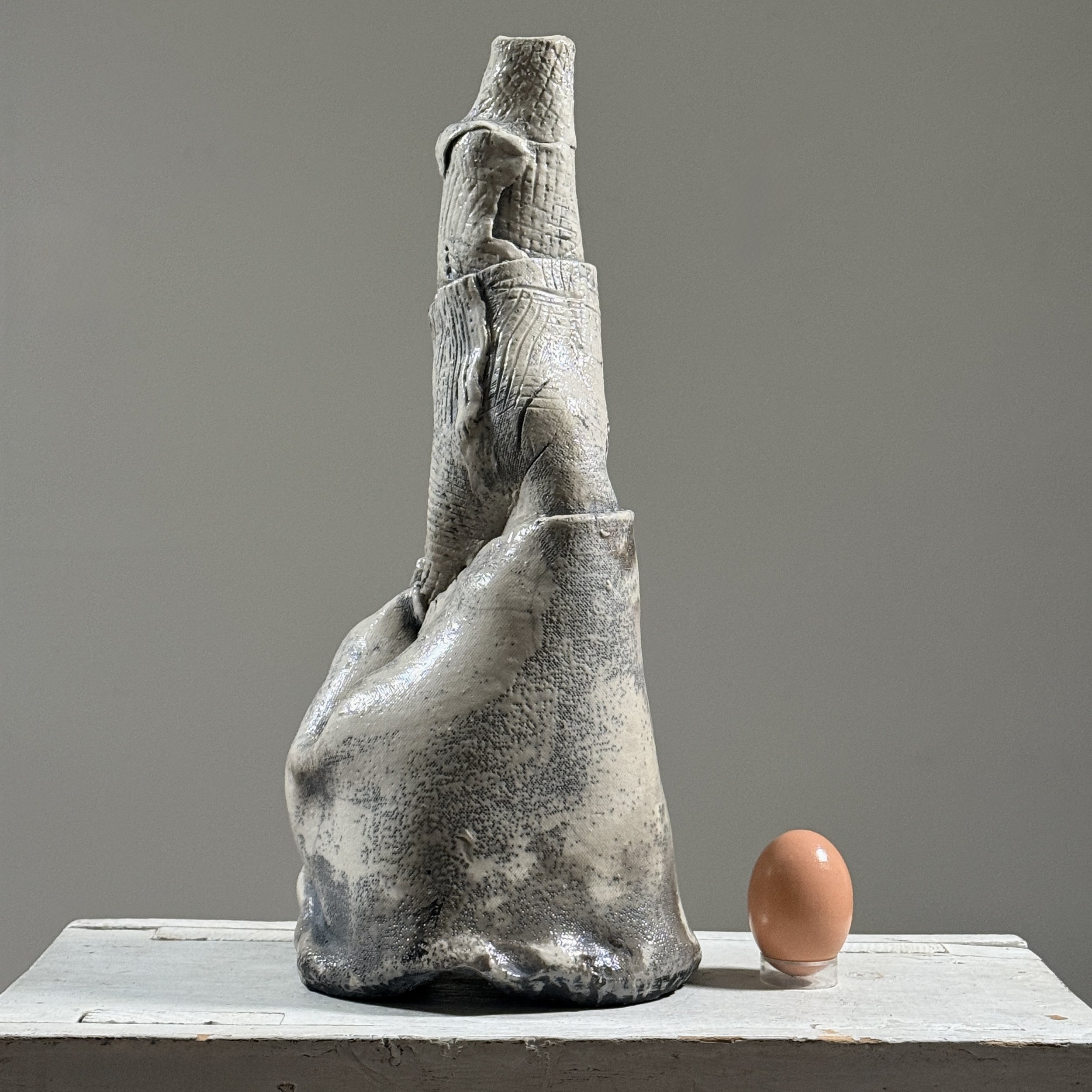 Postmodern abstract raku fired white glazed ceramic vessel With egg for size reference.