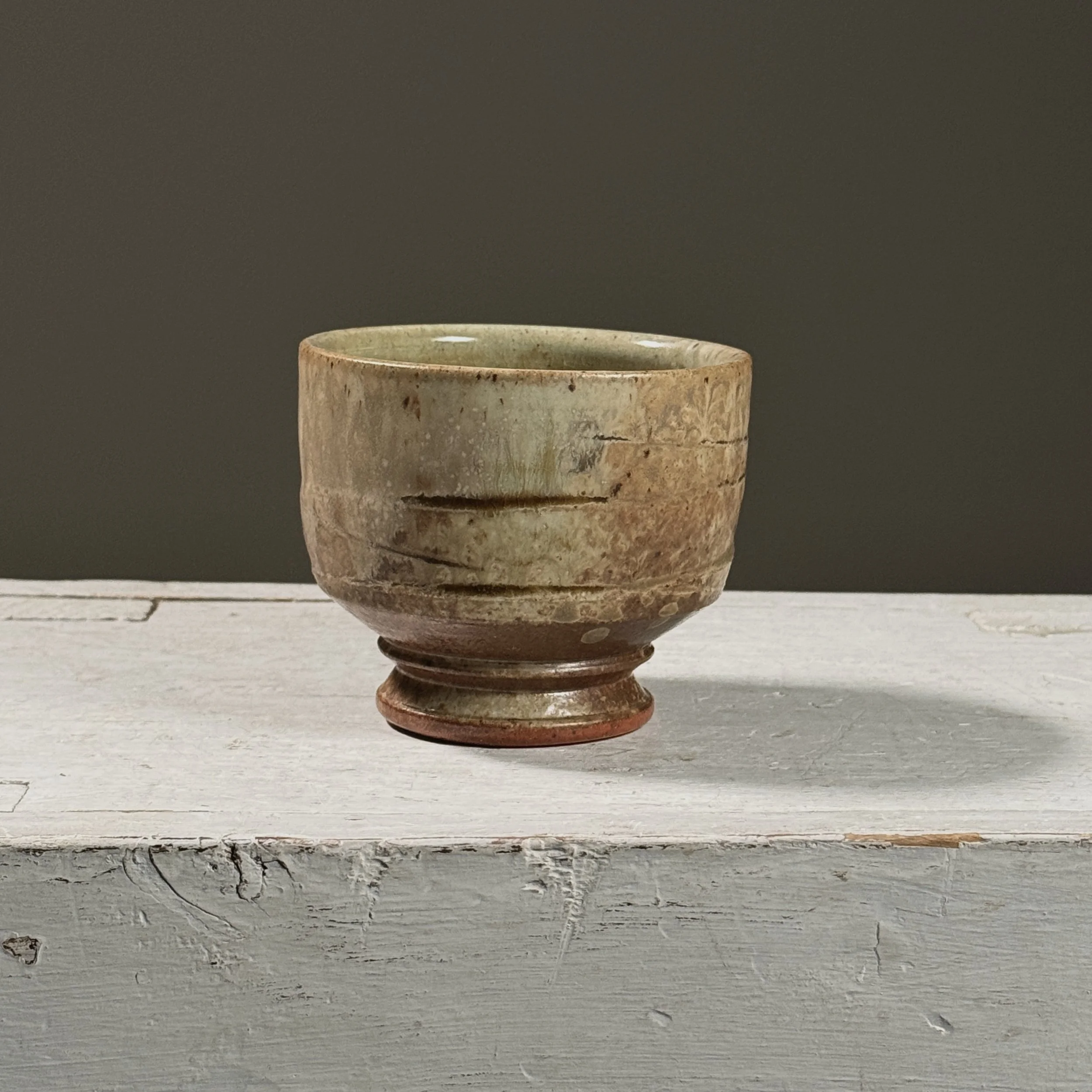 Front view of a vintage wood-fired yunomi with ash and turquoise glaze.