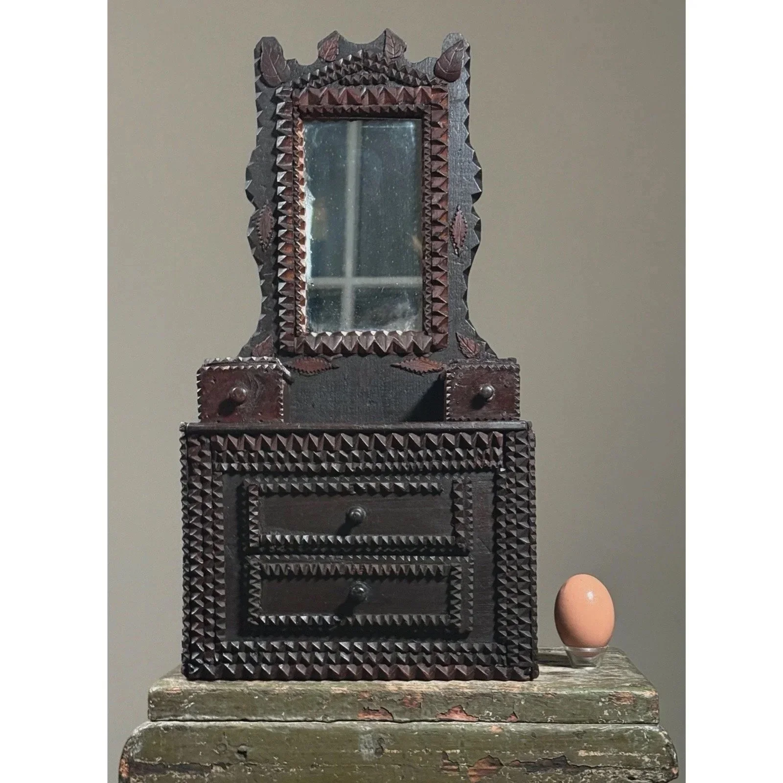 Front view of the antique Tramp Art dresser with mirror with egg for size reference.