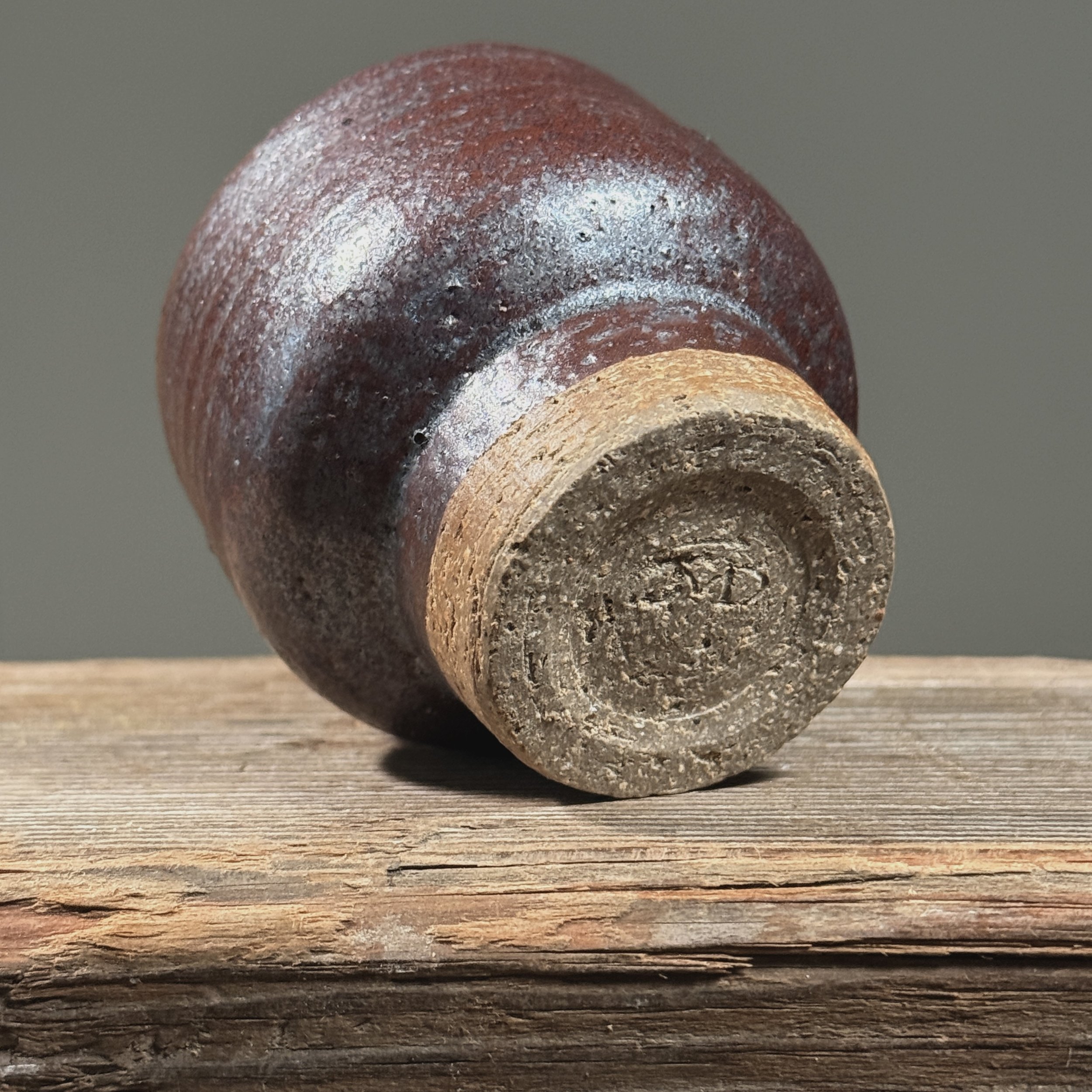 Maroon metallic yunomi cup. Deep maroon surface. Faint blue undertone visible at rim under light.