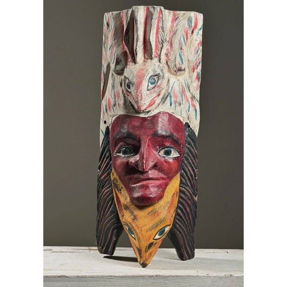 Front view of a vintage Mexican folk art mask with red-painted human face.