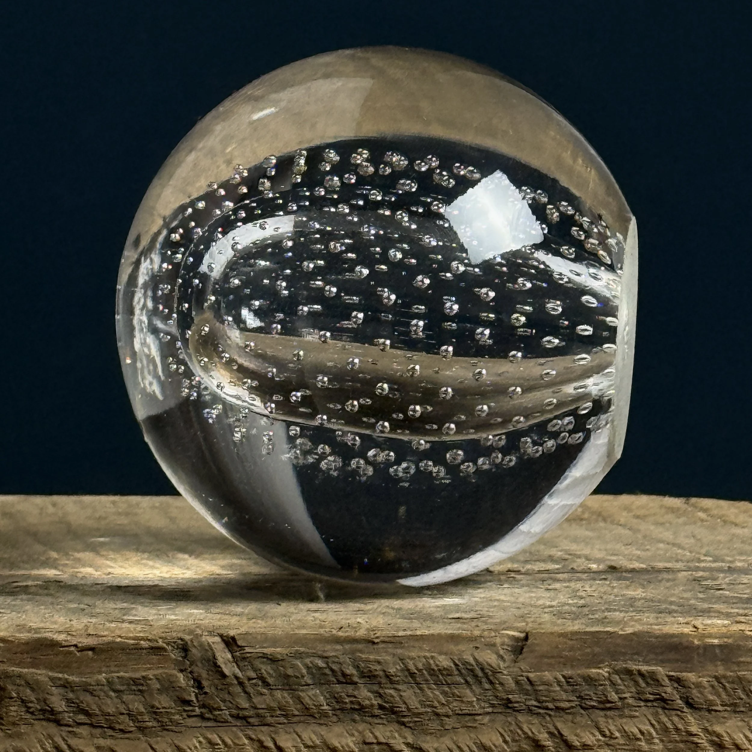 Front view of vintage glass paperweight with oval form and controlled bubbles