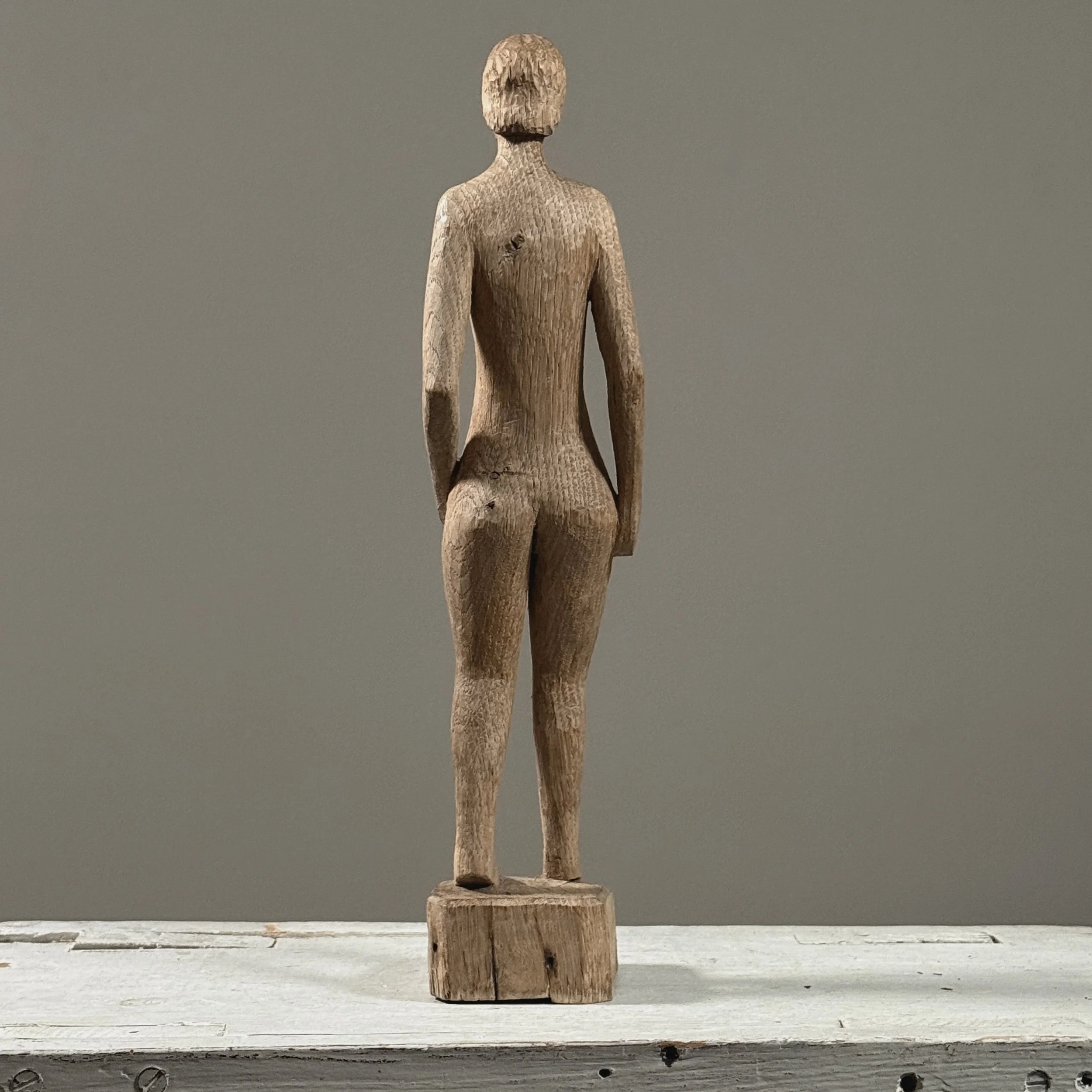 Reverse view of vintage hand carved wood female nude sculpture, showing back of figure and raw wood texture