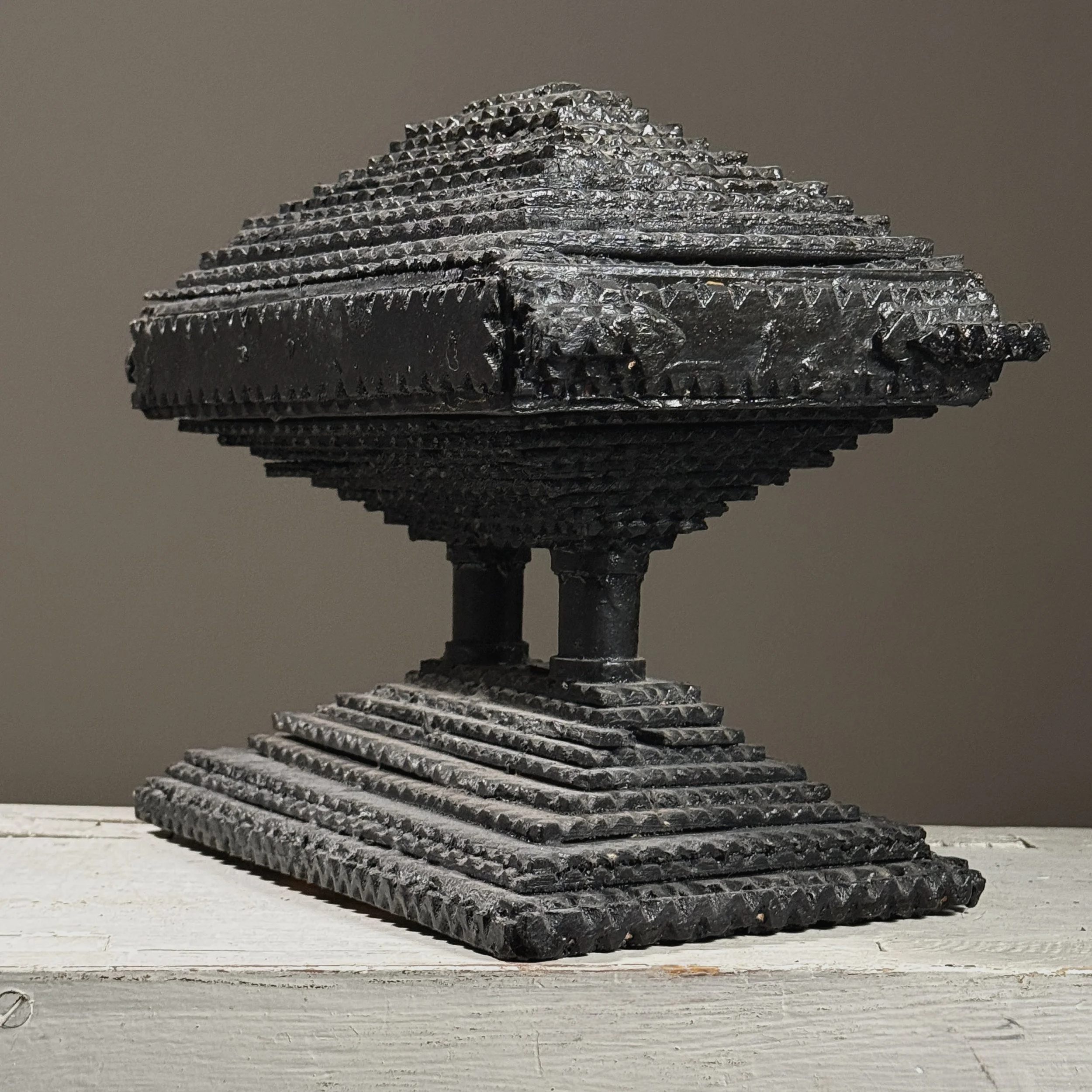 Three-quarter view of a two-tiered tramp art box showing layered chip-carved construction