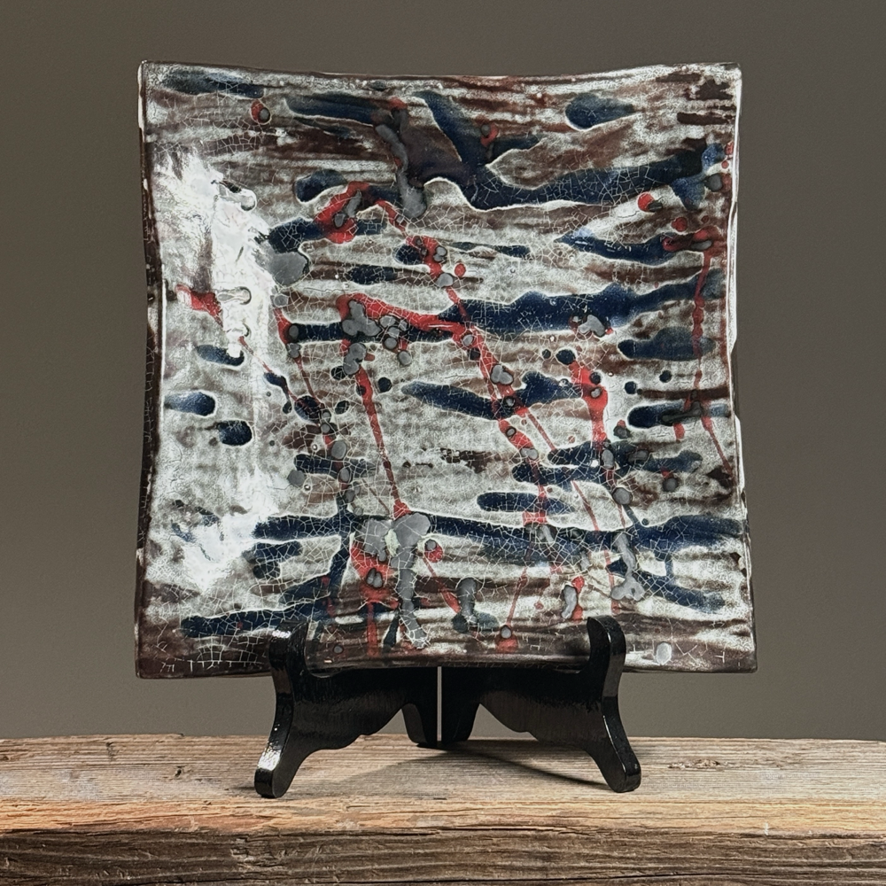 Toshiko Takaezu large slab plate with polychrome splatter glaze in deep blue, crimson red, and cool grey.
