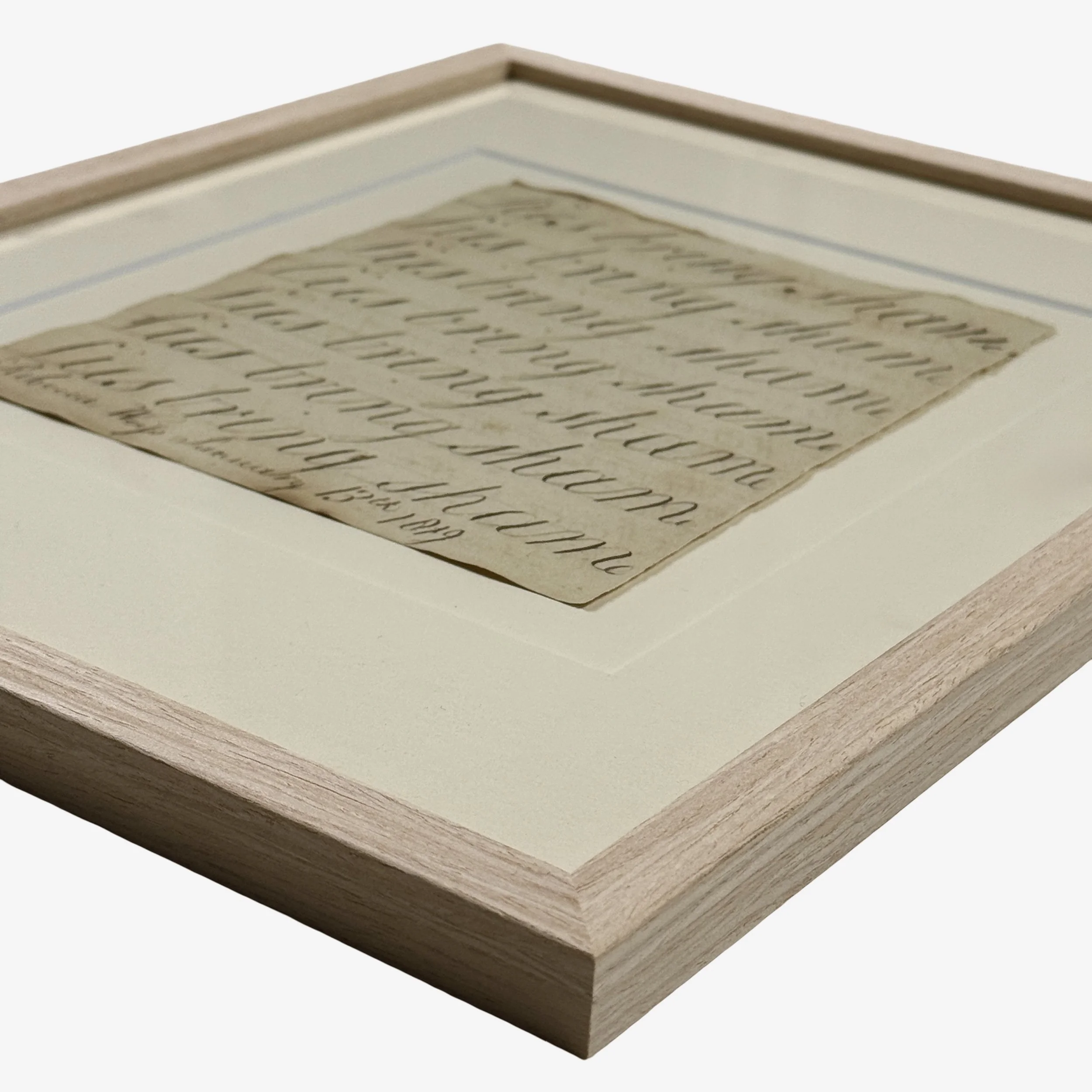 Framed antique calligraphy under glass in blond wood frame