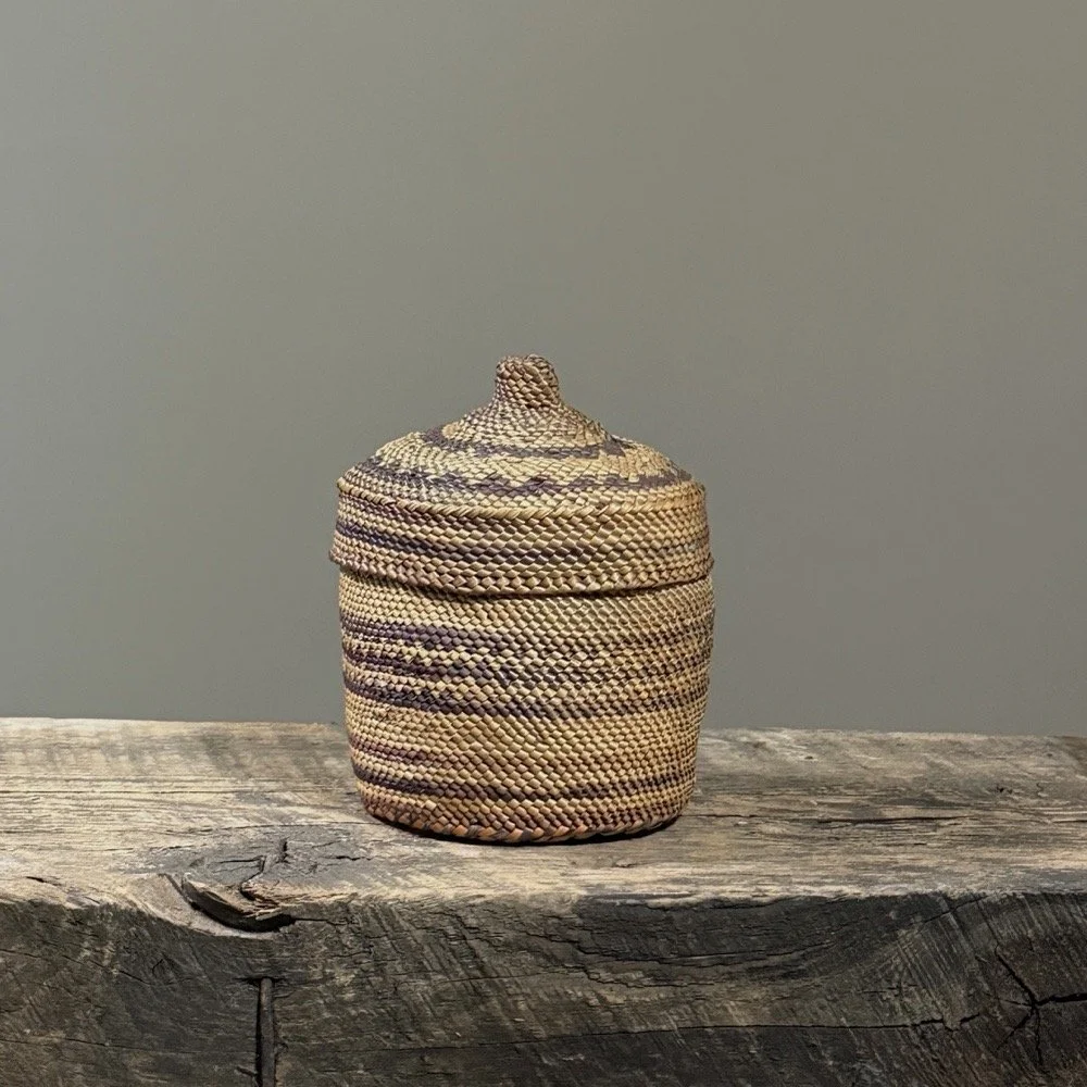 Full frontal view of an antique Makah woven lidded basket with purple geometric decoration