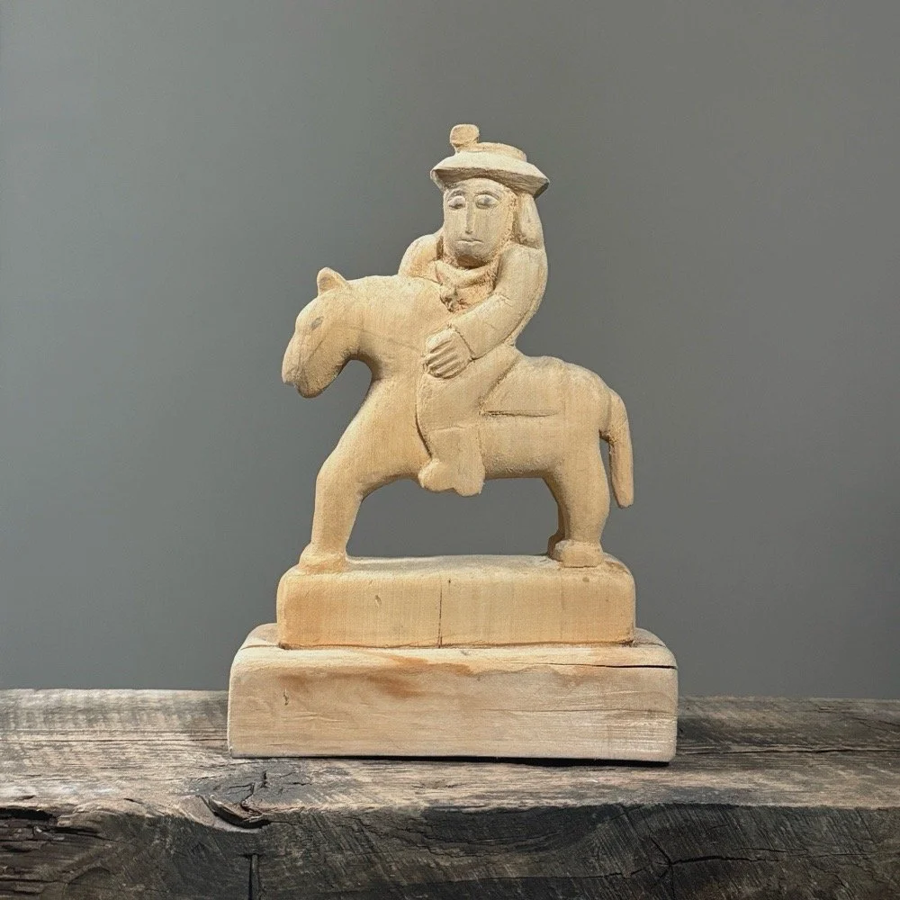 Front view of a vintage hand-carved wooden horse and rider sculpture.