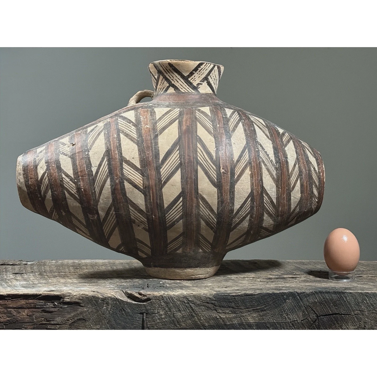 Majiayao-style vessel showing elongated body form with egg for size reference.