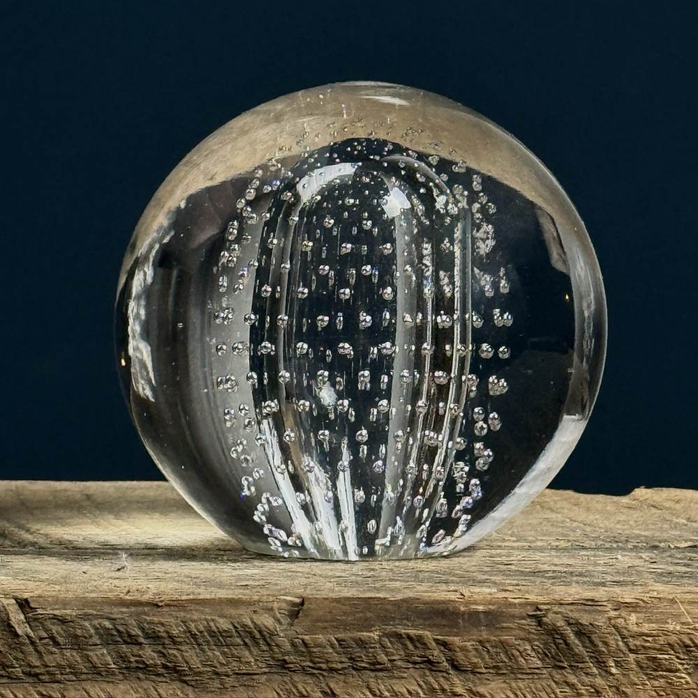 Front view of vintage glass paperweight with oval form and controlled bubbles