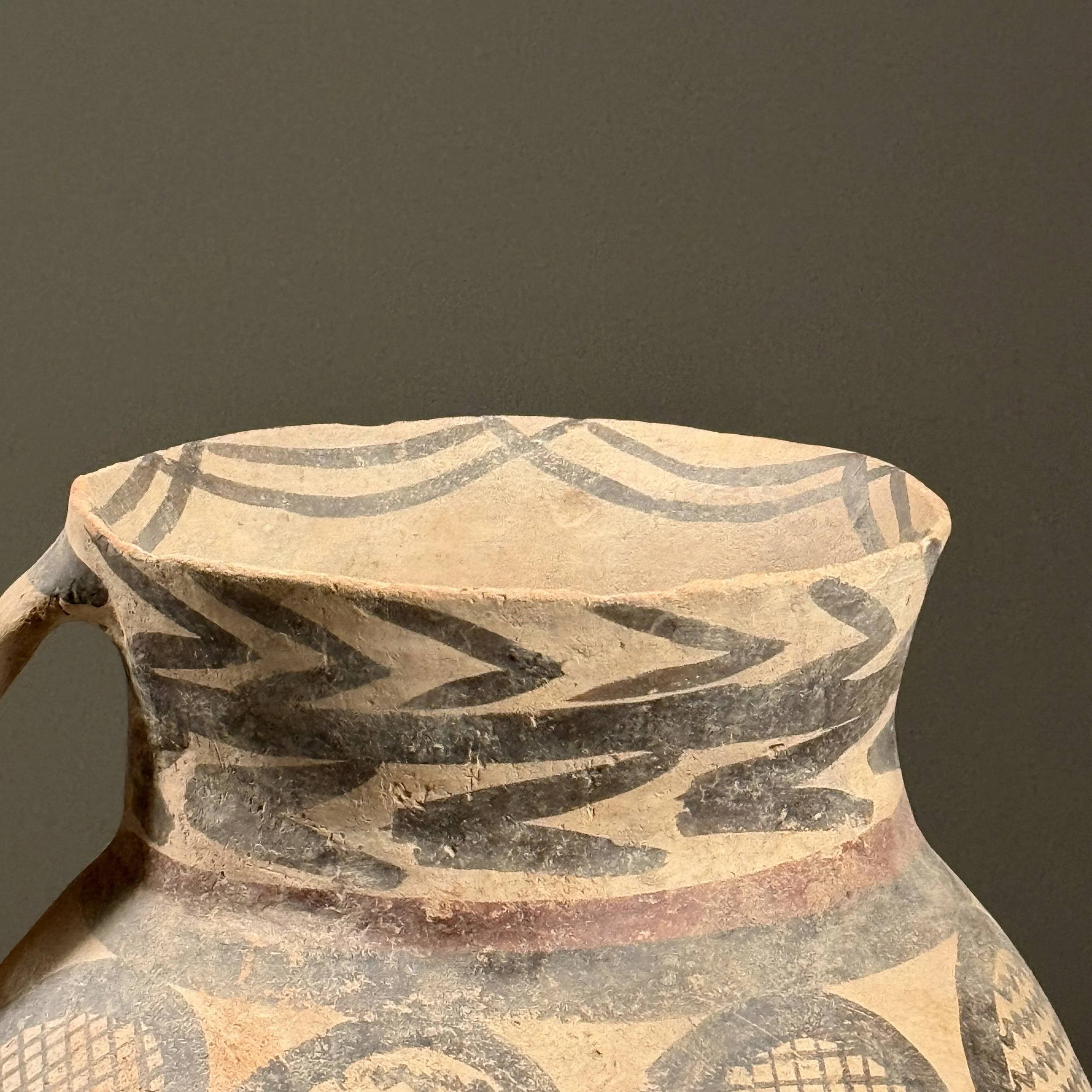 Close-up detail of zigzag and concentric band patterns painted on a vintage Chinese ceramic vessel