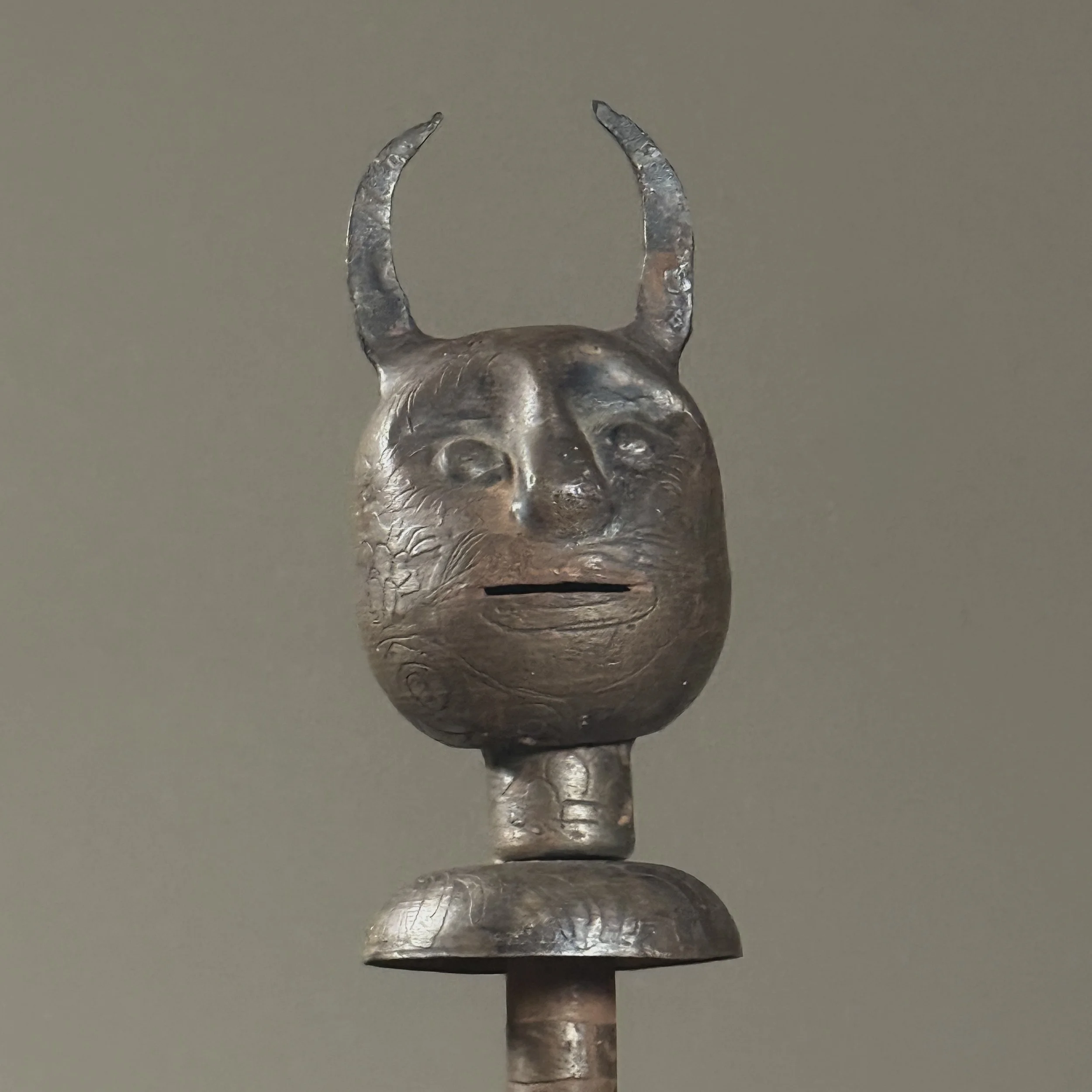 Close-up of forged devil face mace head showing etched features and dark patina