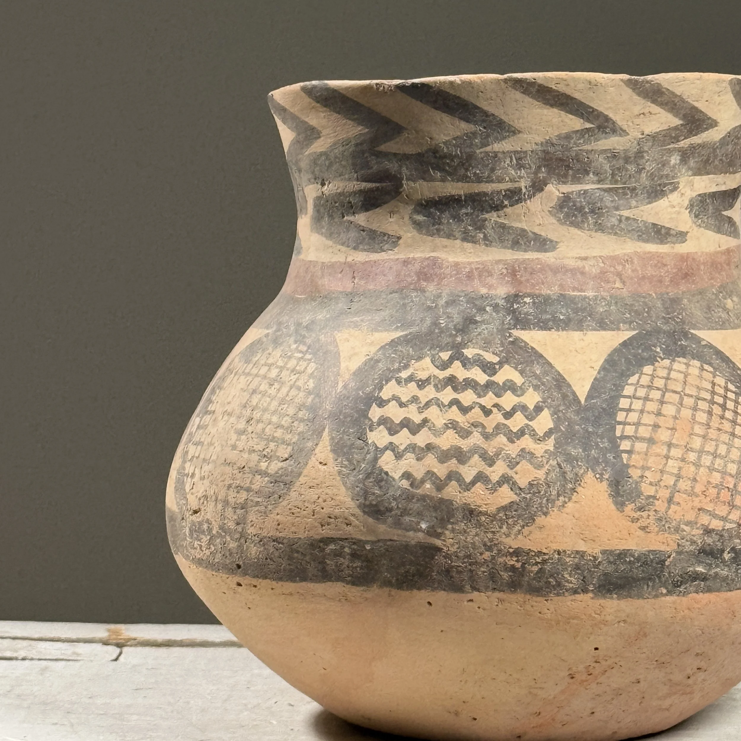 Close-up detail of zigzag and concentric band patterns painted on a vintage Chinese ceramic vessel