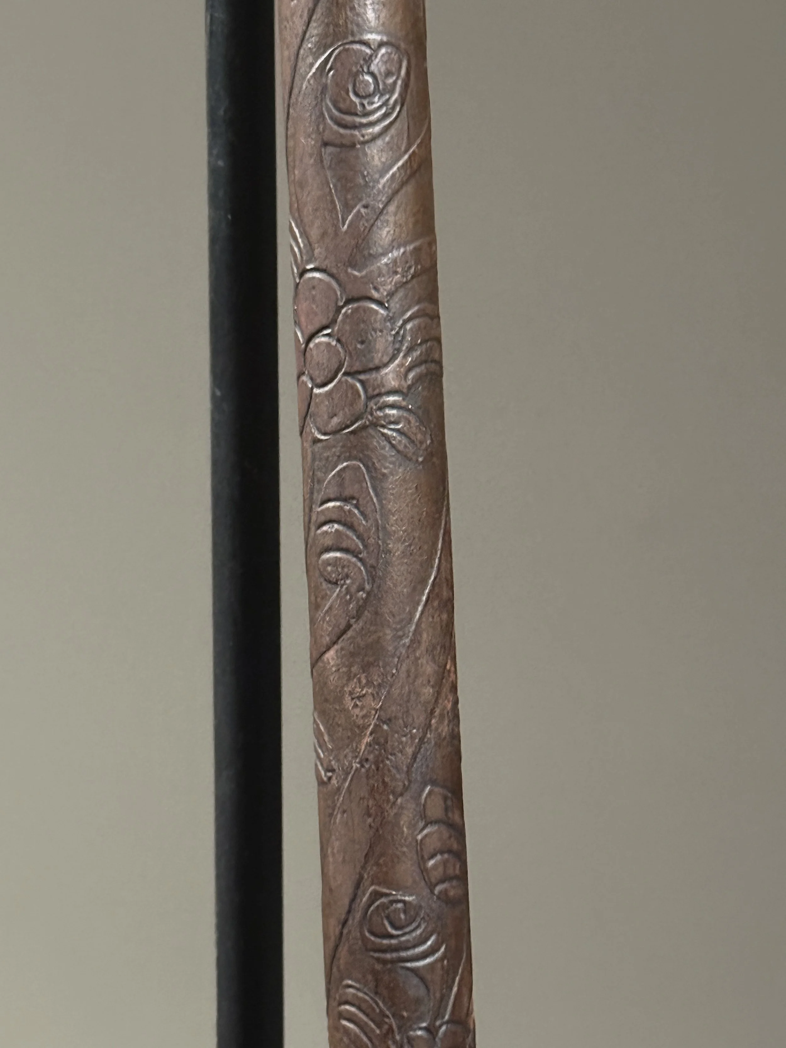 Surface detail showing oxidation pattern and minor abrasions on etched staff decoration