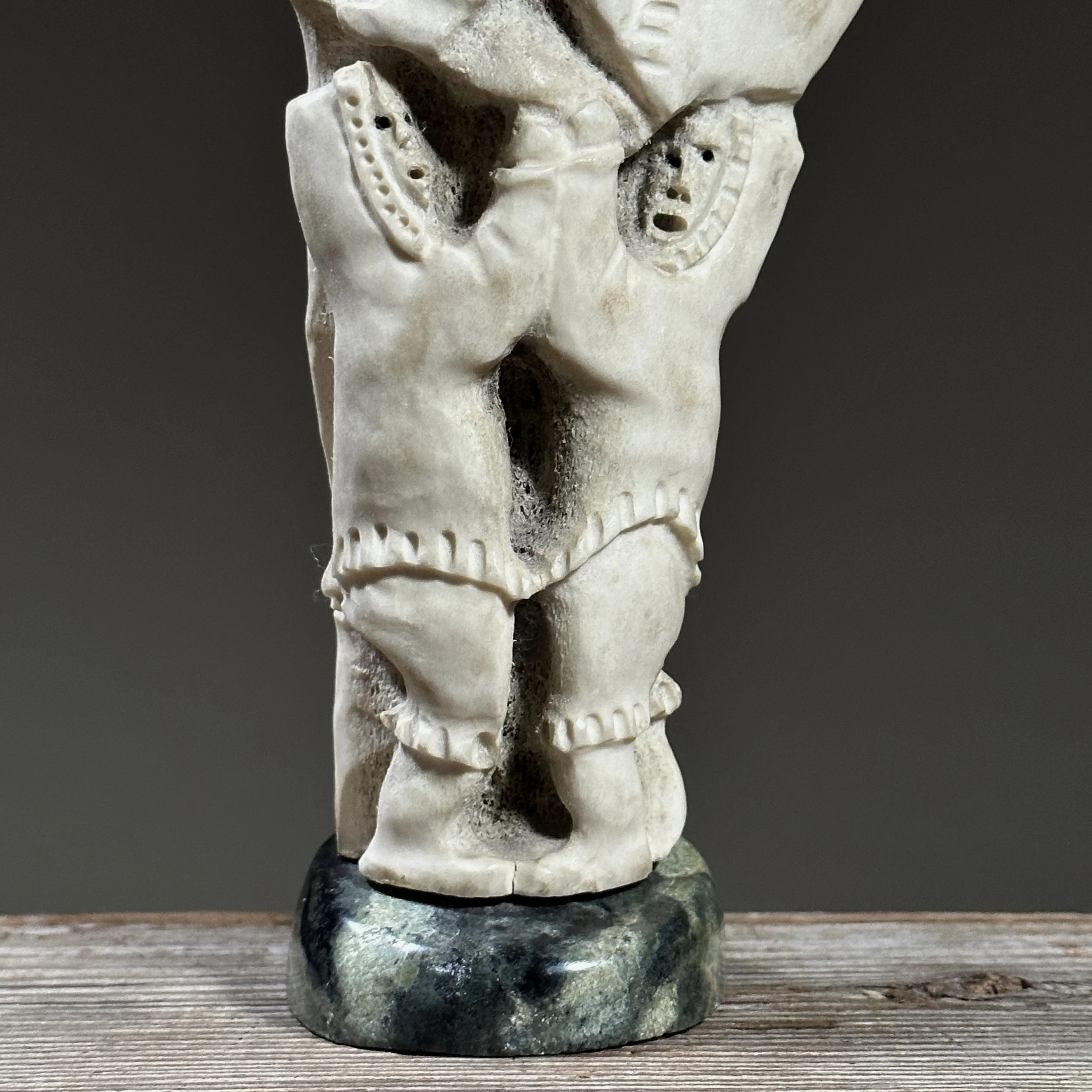 Detail of carved figures emerging from the antler form.