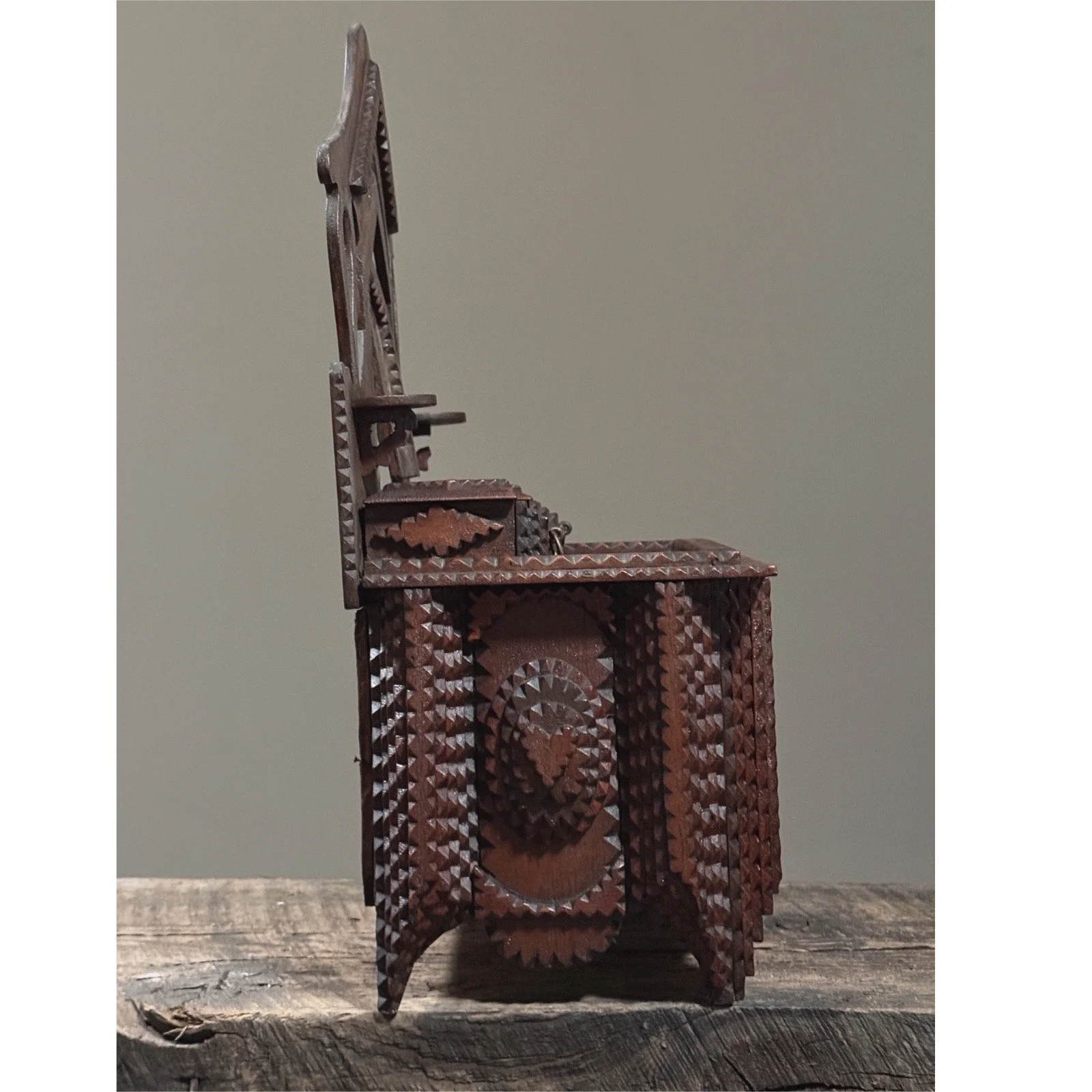 Side view of antique chip-carved tramp art dresser with two drawers